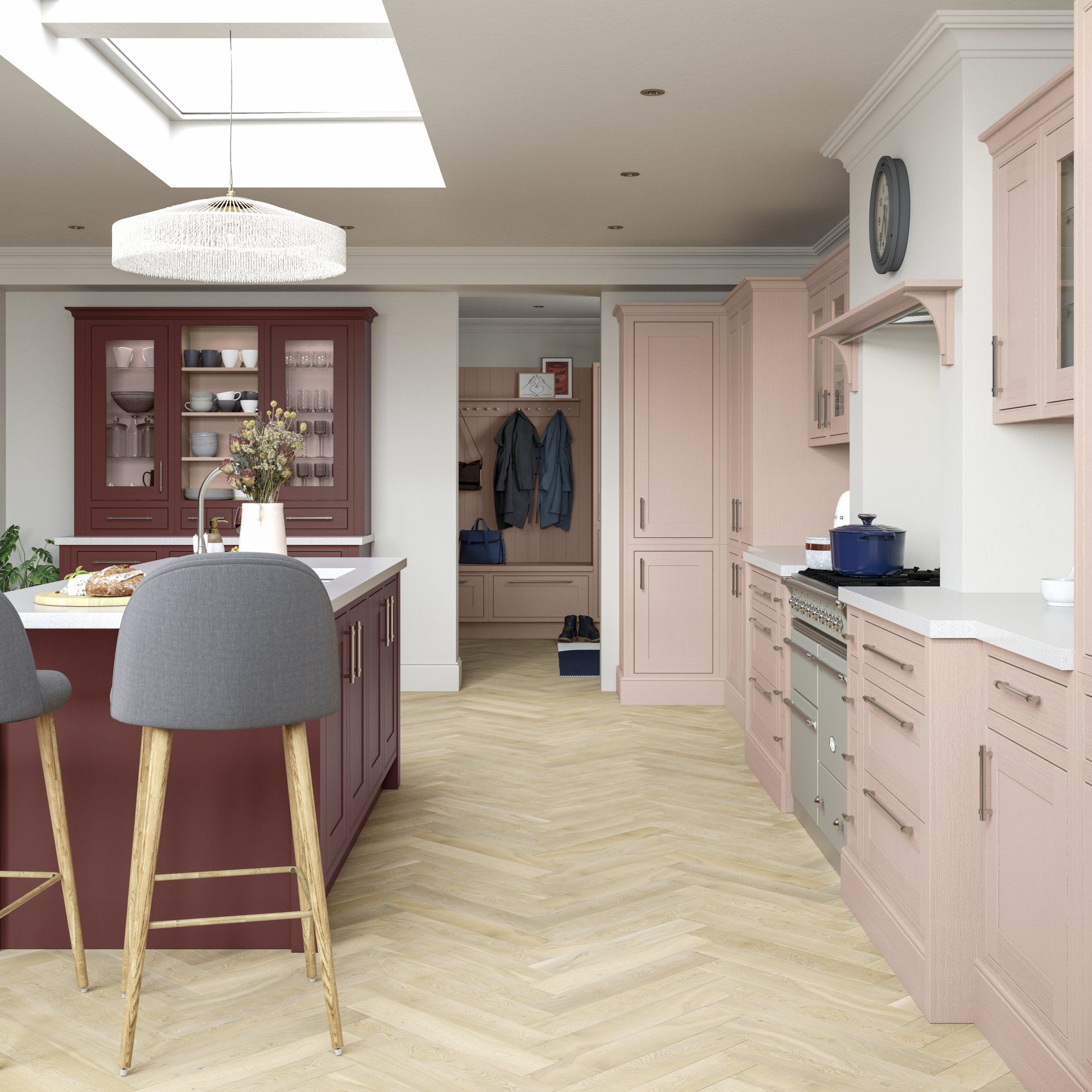 A kitchen with a maroon island and cabinets, blush pink cabinets, a gray bar stool, and light wood herringbone flooring.