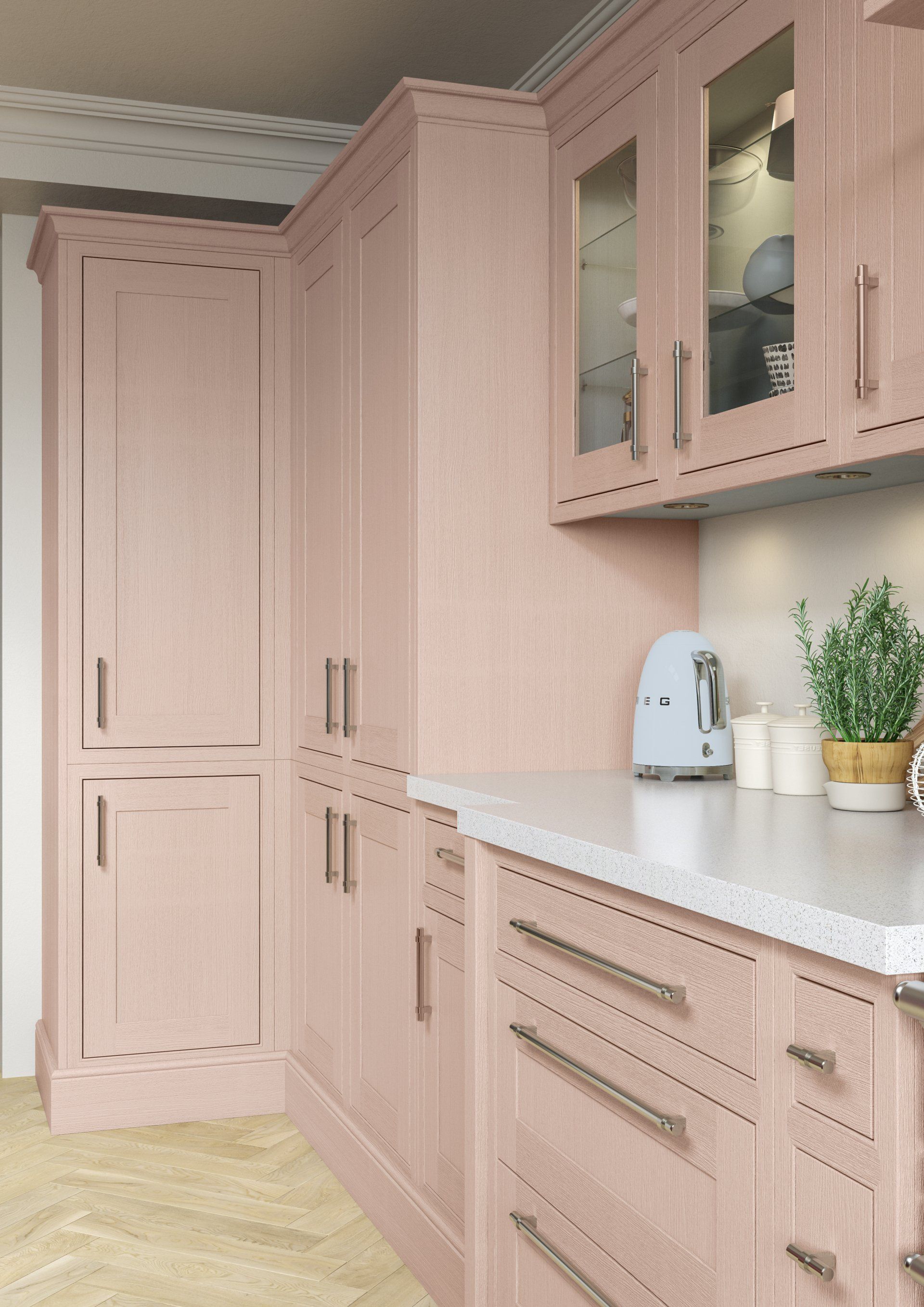 A modern kitchen featuring pale pink cabinets, brushed metal hardware, white countertops, and a herringbone floor.