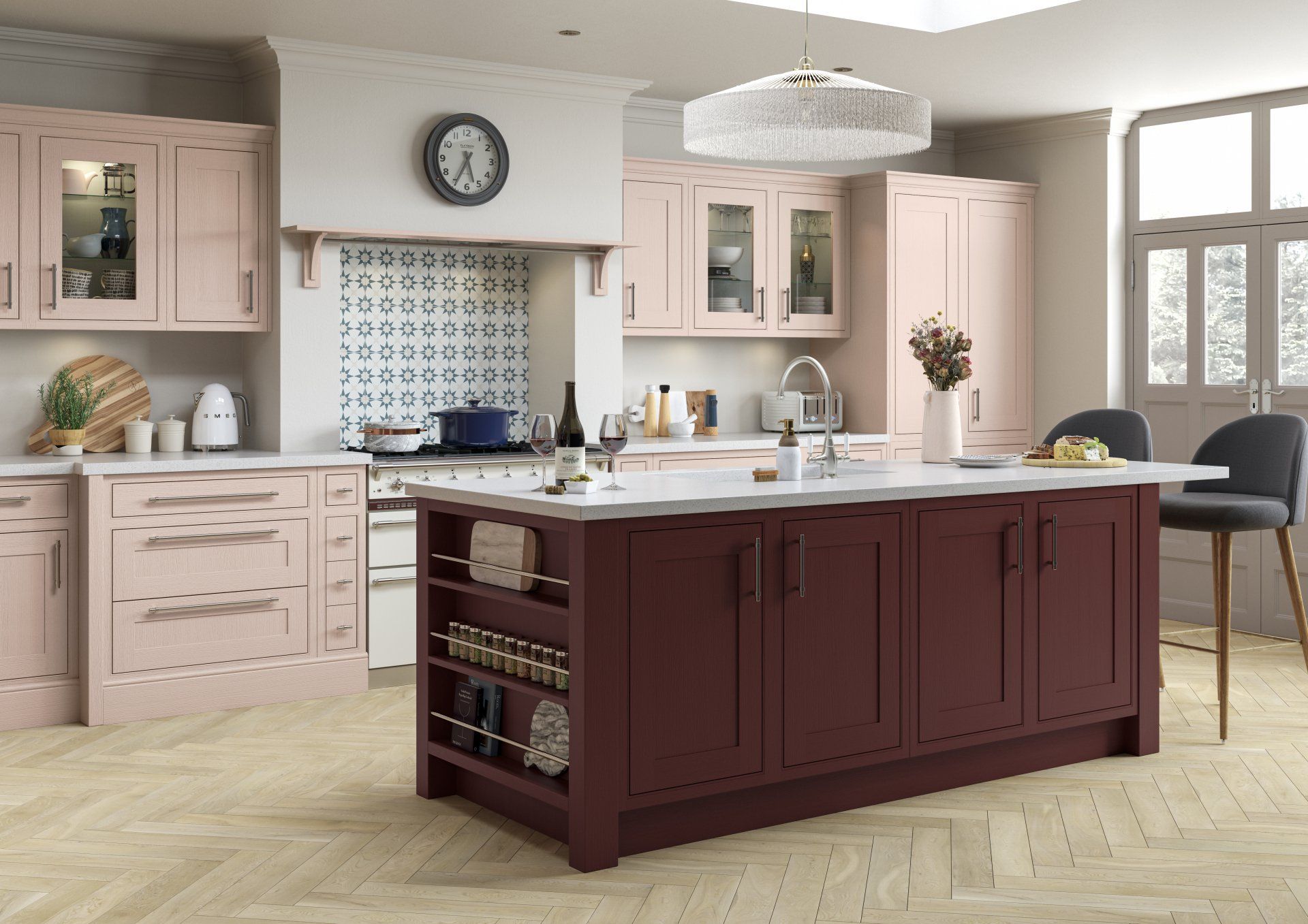 Modern kitchen featuring a dark maroon island, blush pink cabinetry, white countertops, and light herringbone flooring.