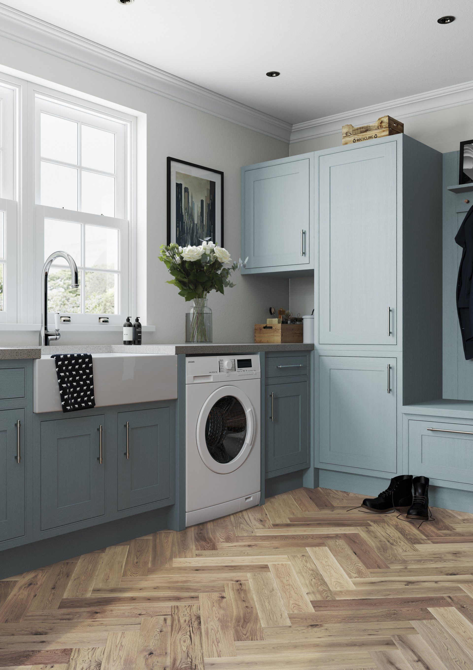 A utility room with grey cabinets, a farmhouse sink, a washing machine, and light wood herringbone flooring.