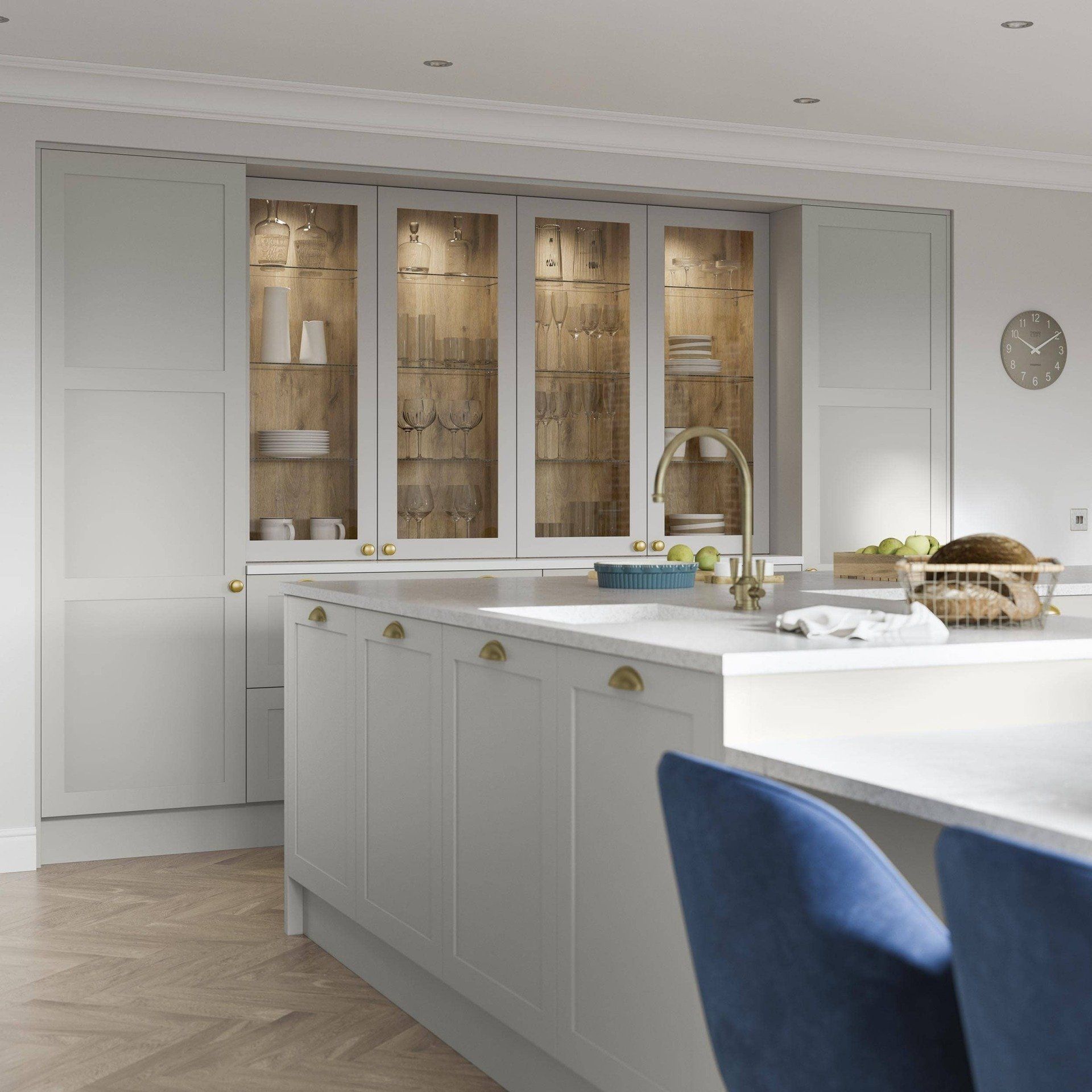Modern white kitchen island and cabinets with glass-front display shelves, wood accents, and blue velvet bar stools.