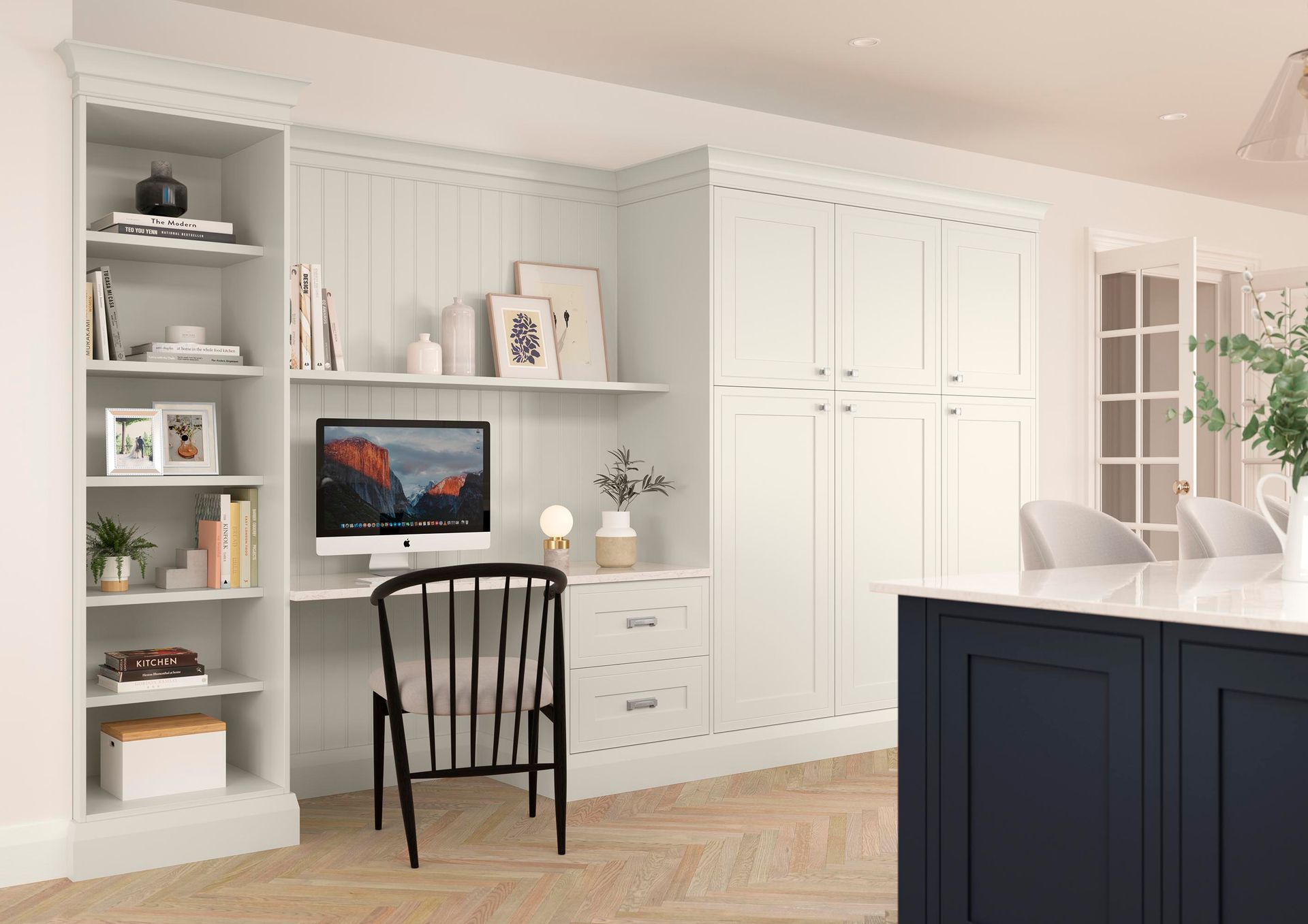 Bright home office with built-in shelves, a desk, white cabinets, and a dark kitchen island in the foreground