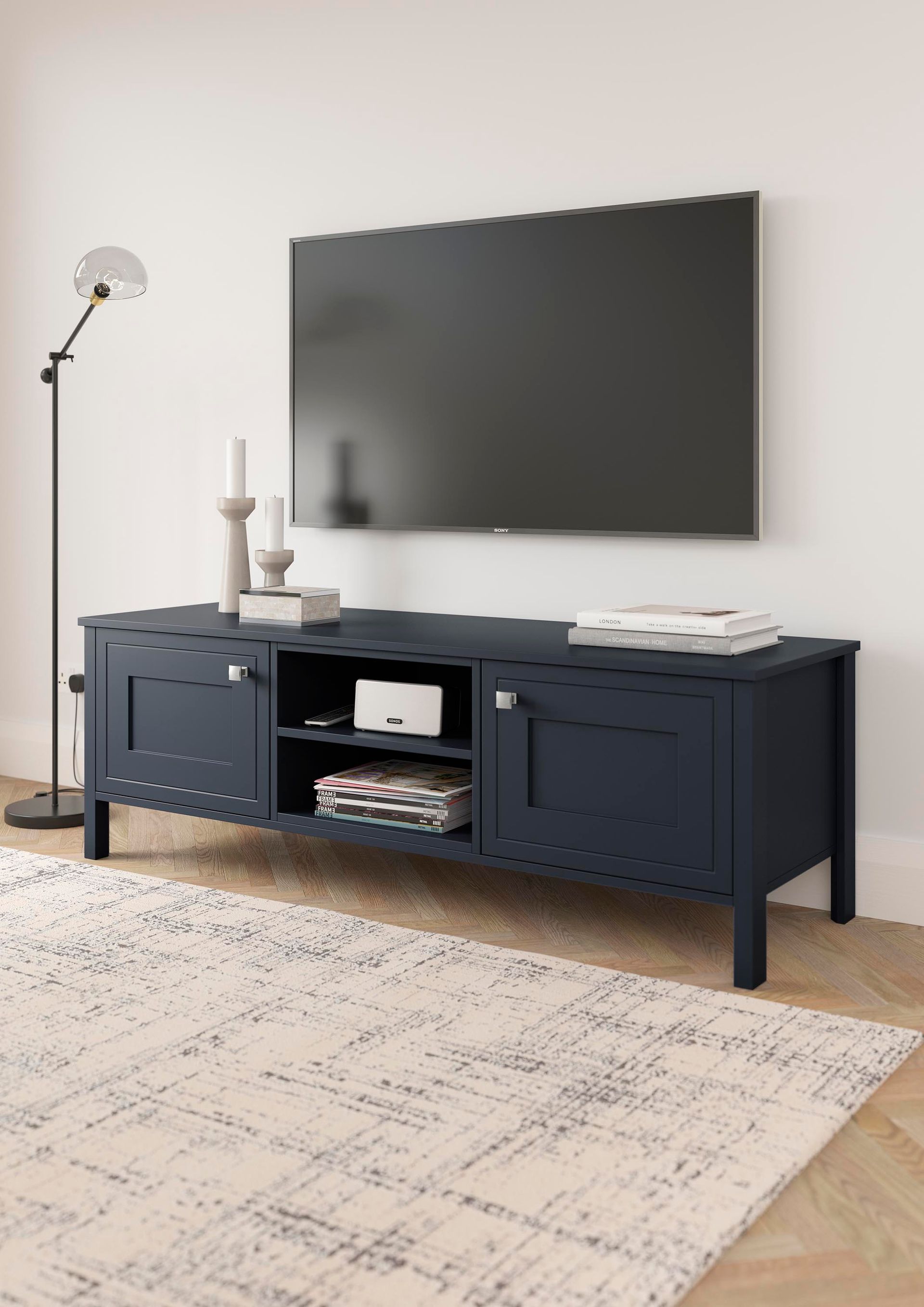 Modern living room with wall-mounted TV above a dark media console and a light patterned rug