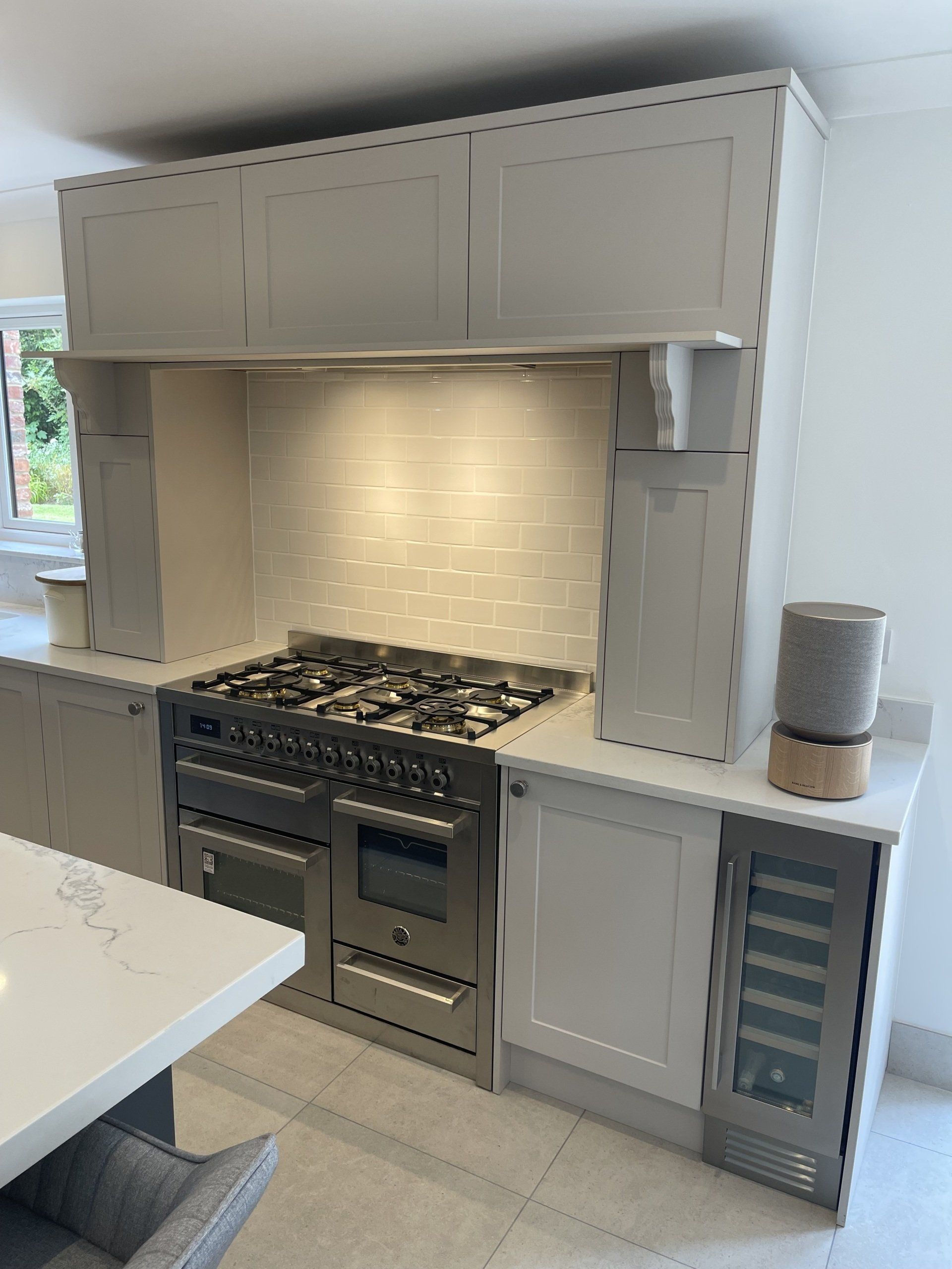 A modern kitchen featuring a stainless steel range stove, a white tiled backsplash, and light gray cabinetry.
