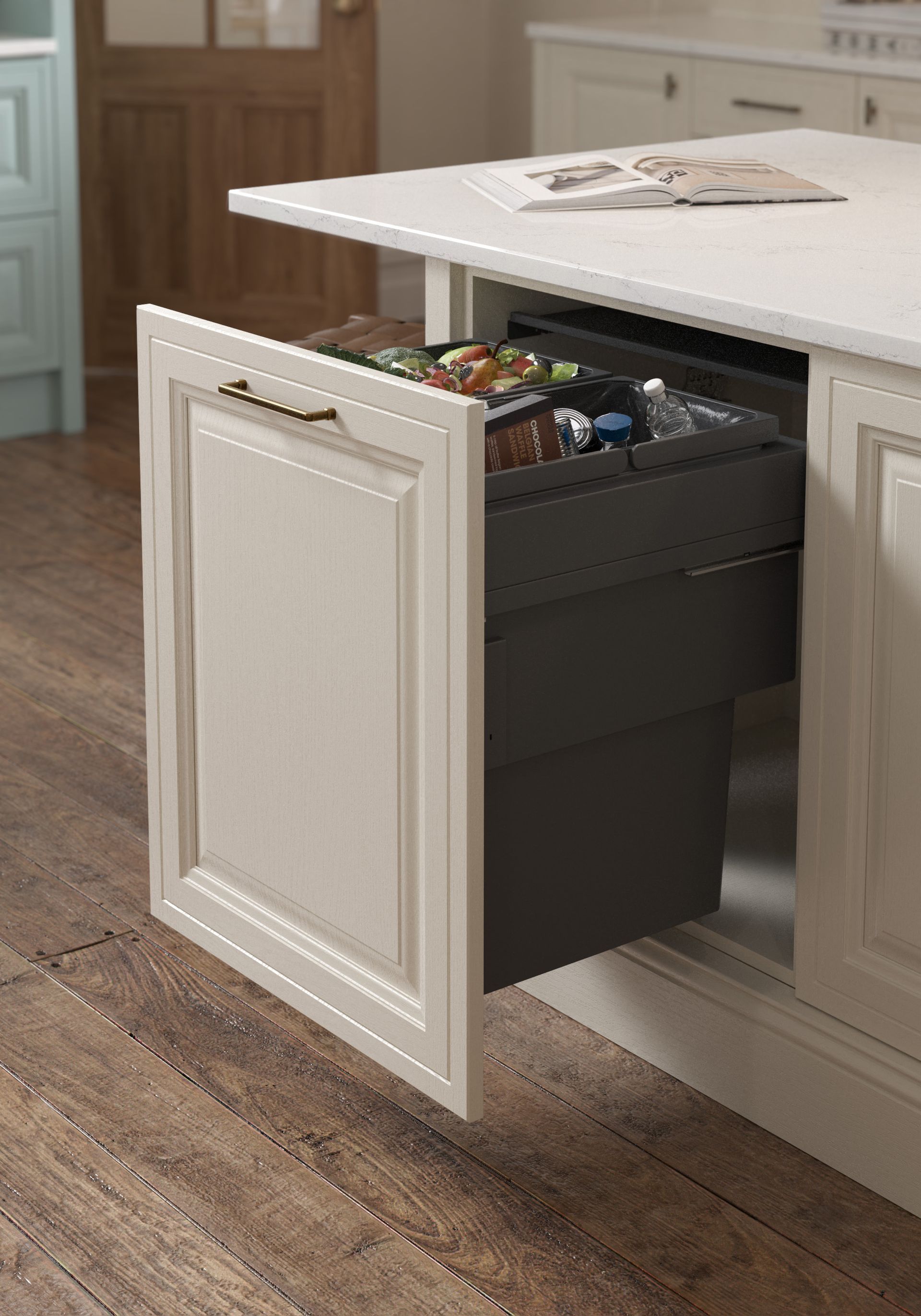 A cream-colored kitchen island drawer pulled open to reveal a built-in dark gray waste bin inside.