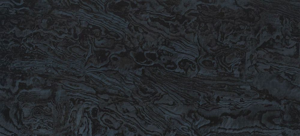A close-up of dark charcoal-colored stone with flowing, organic marbled patterns and subtle variations in texture.