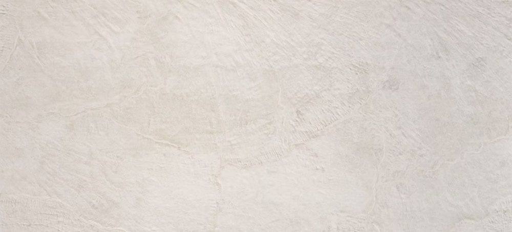 A full-frame view of a light beige stone surface with a subtle, textured, and weathered matte finish.