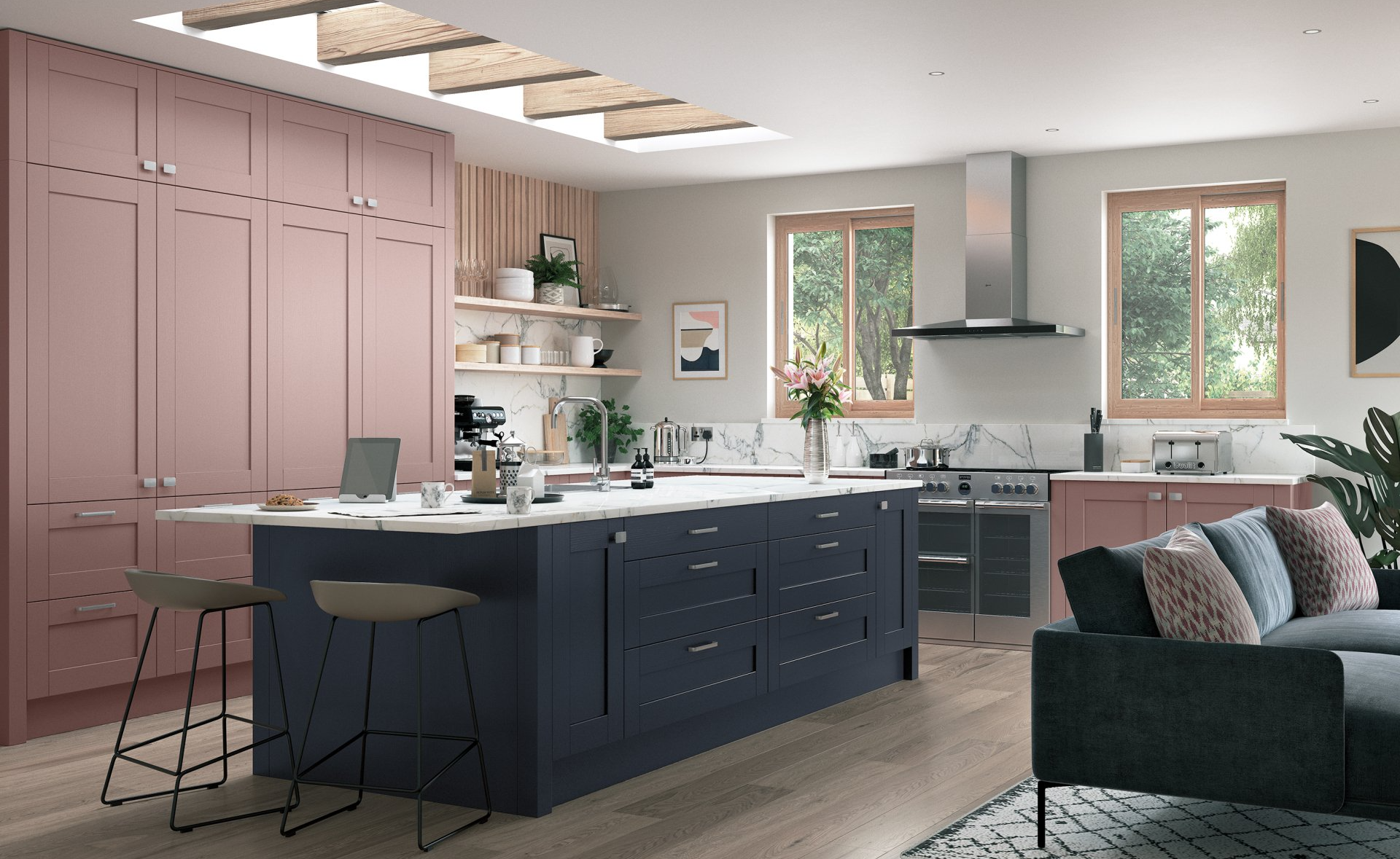 A modern, open-concept kitchen featuring a dark blue island with bar stools against a wall of dusty pink cabinetry.