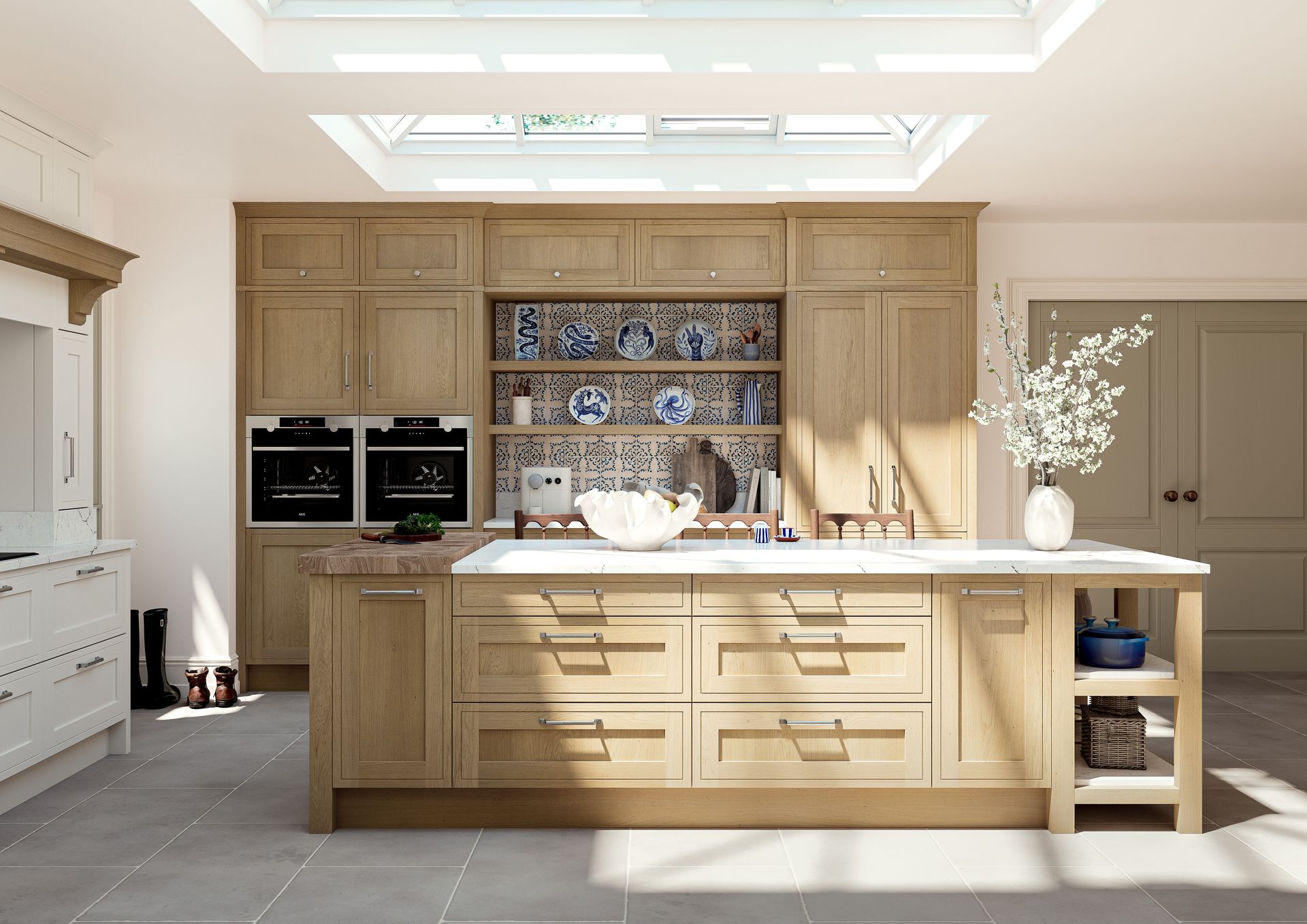 A spacious, modern kitchen featuring light wood cabinetry, a large central island, double ovens, and decorative plates.