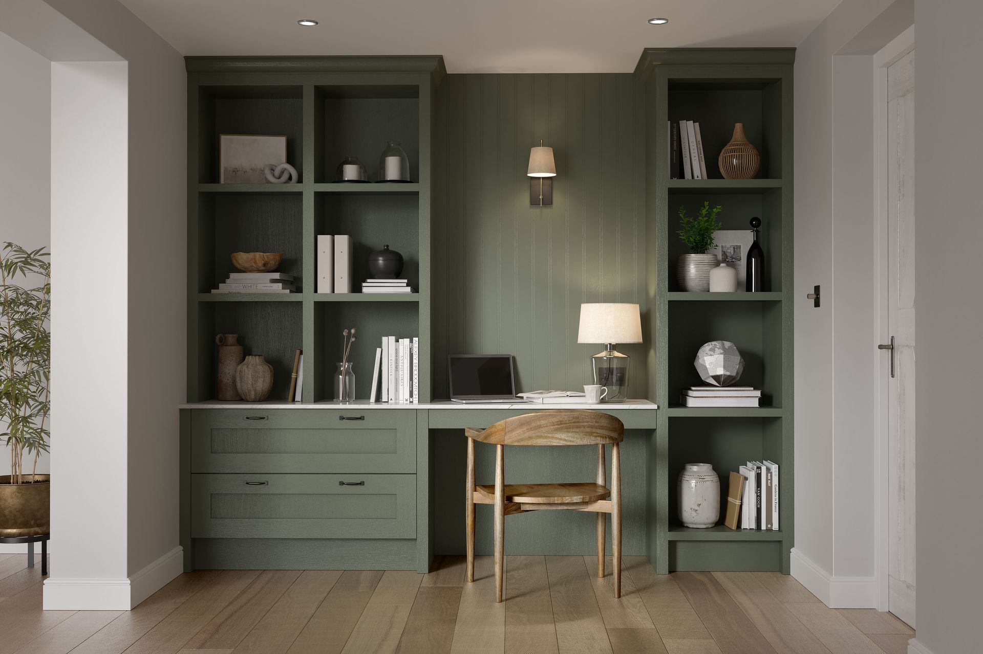 A home office featuring sage green built-in shelves and a desk with a wooden chair against a paneled wall.