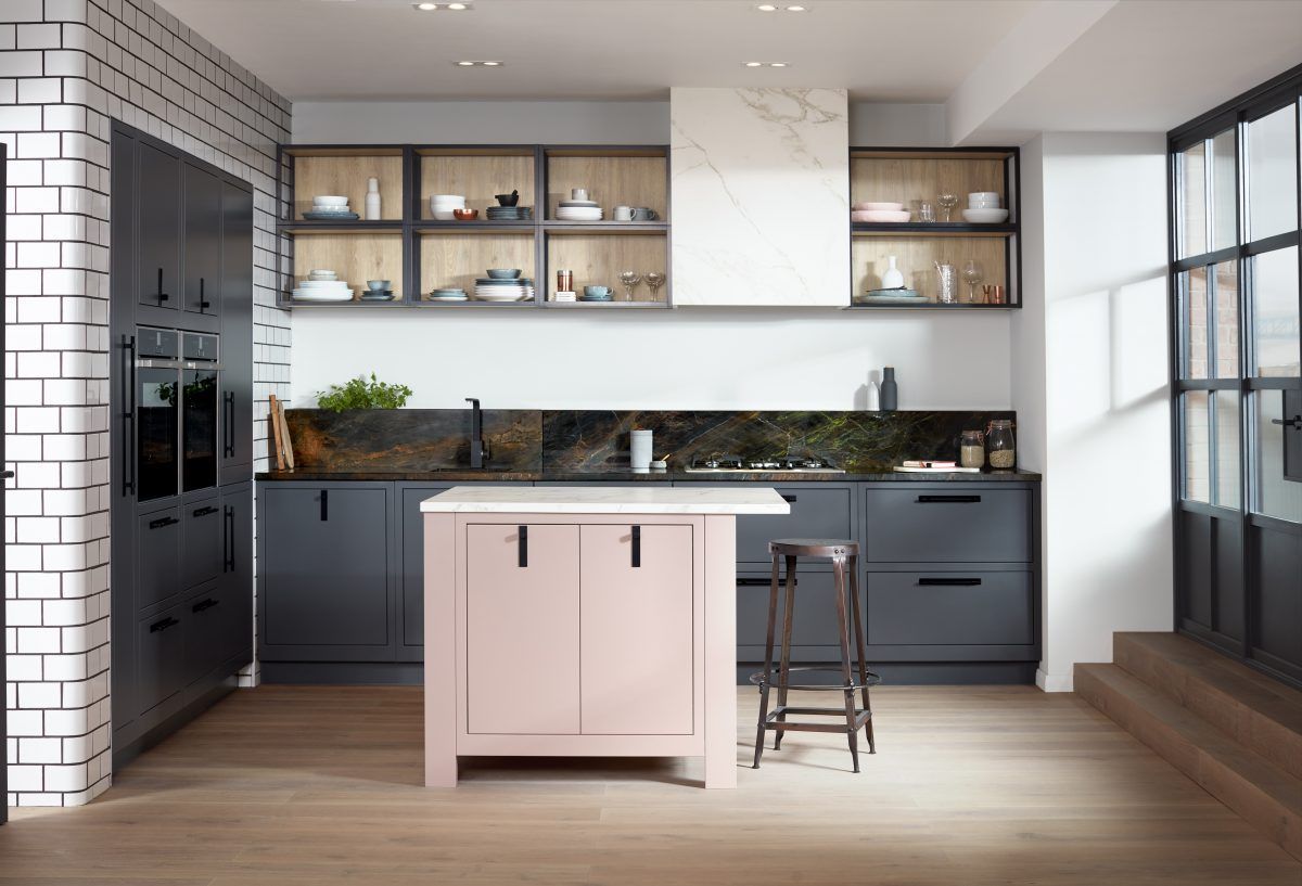 A modern kitchen featuring dark grey cabinets, wood-toned open shelving, a white stone range hood, and a light pink island.