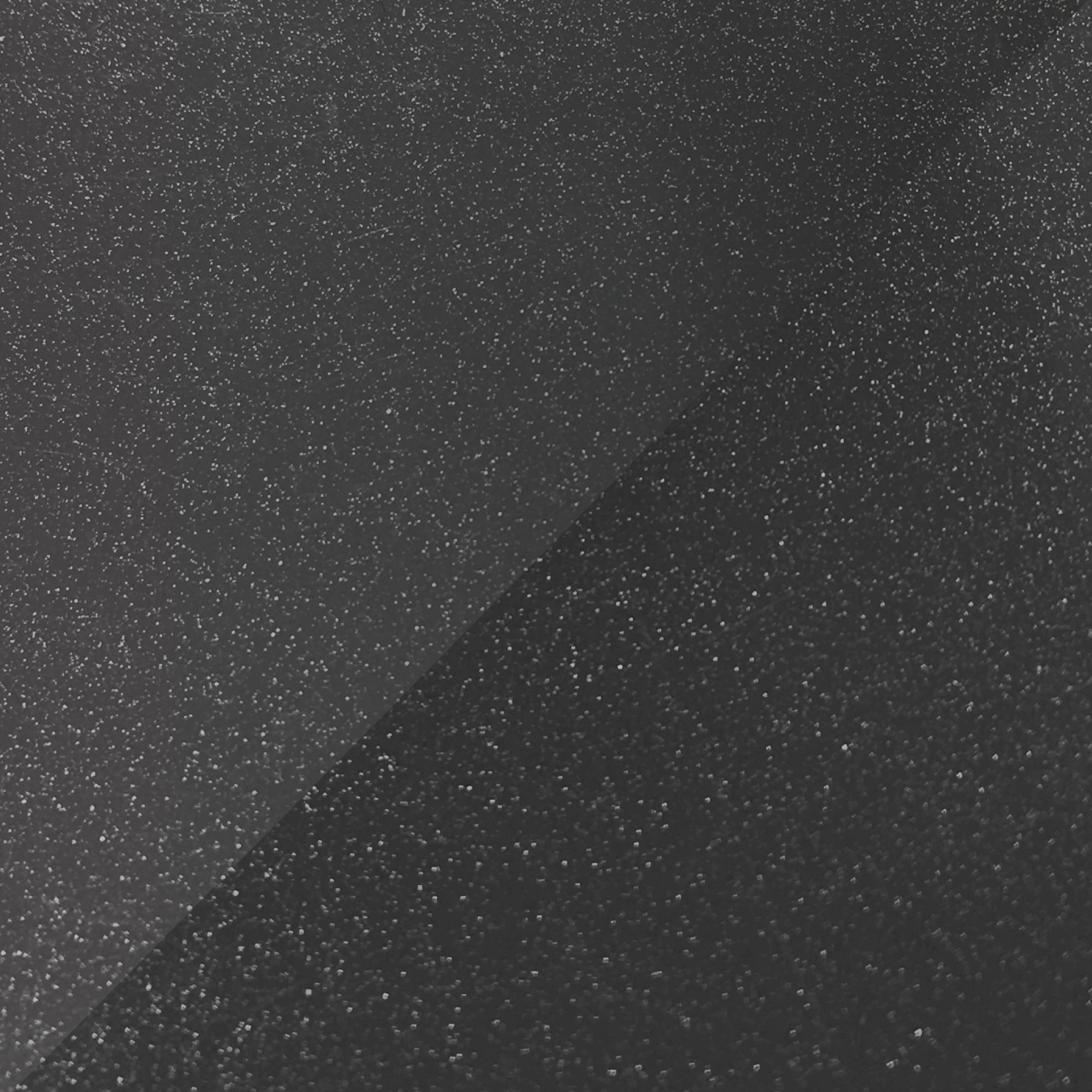 A diagonal split shows a dark grey, grainy, metallic-like surface on the left and a darker, textured black on the right.