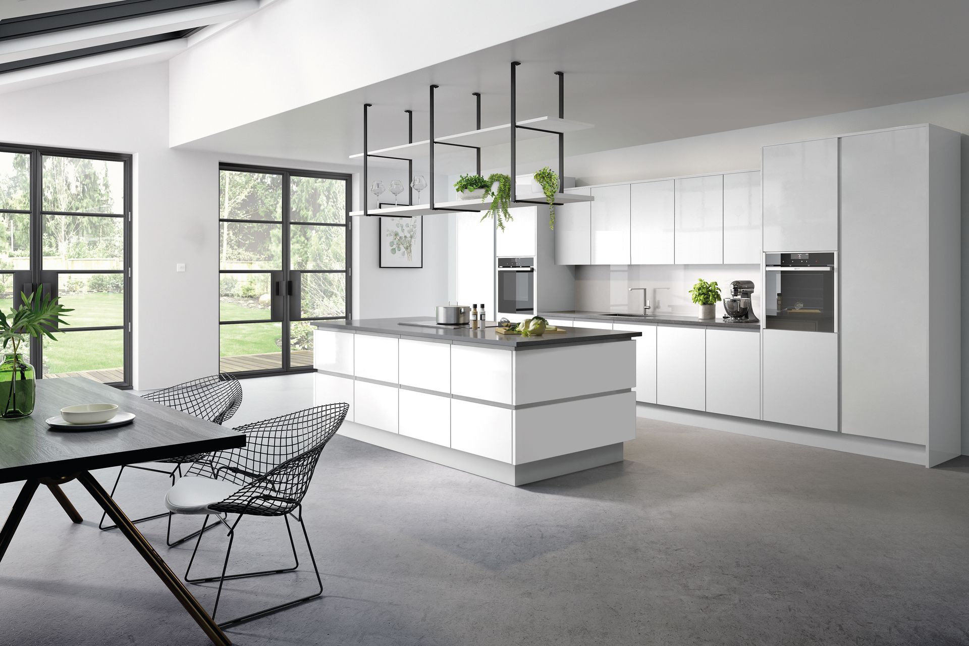 Modern white kitchen with a central island, hanging shelf, and dining area with chairs against a floor-to-ceiling window.