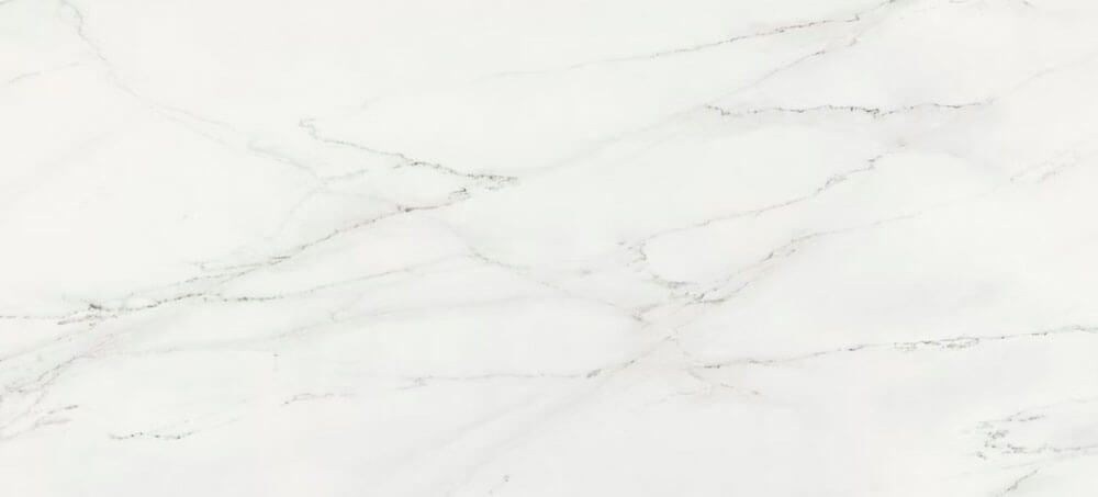 A close-up of white marble stone with thin, light grey veining flowing across the surface.