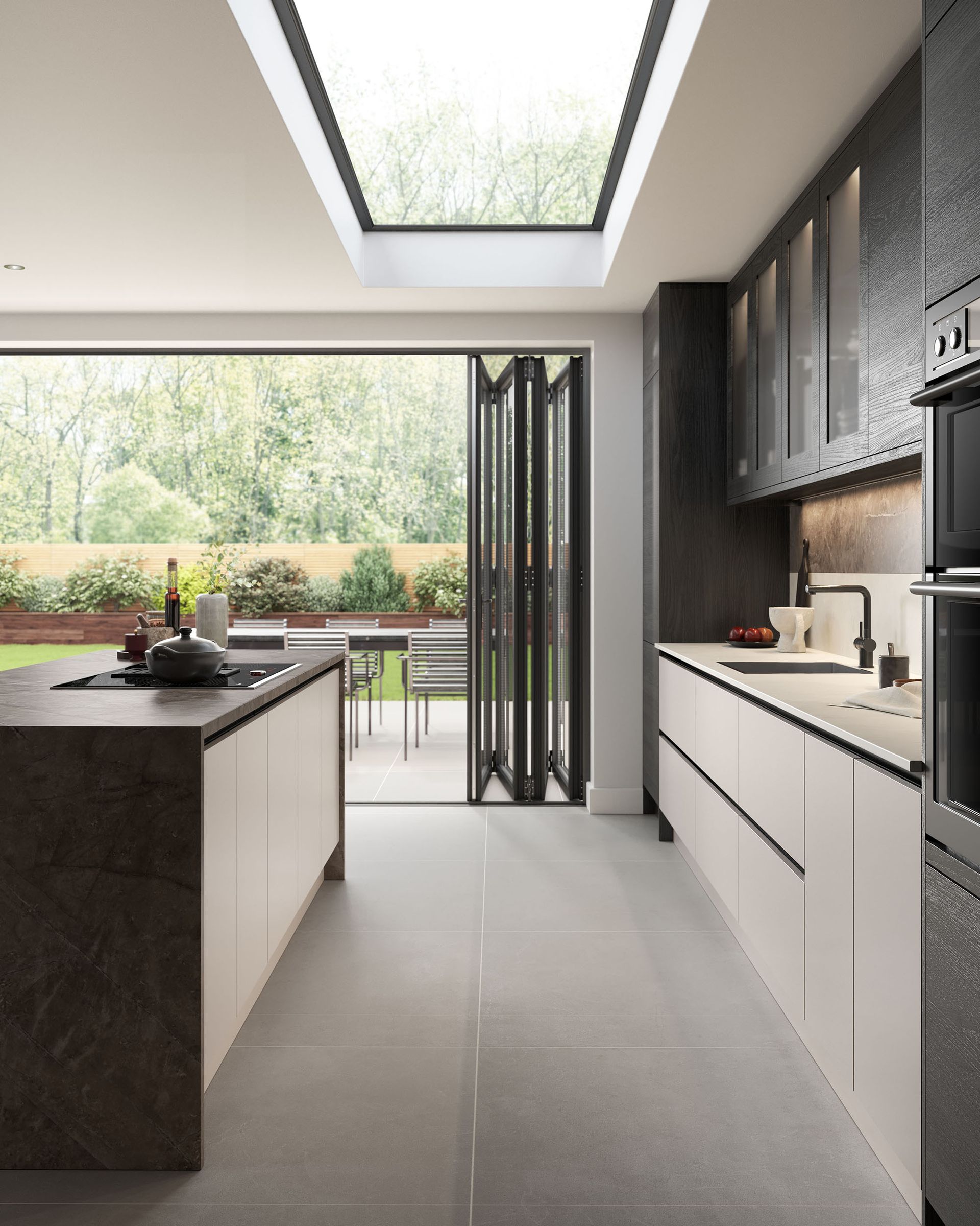 A modern kitchen featuring a dark island, light cabinets, a skylight, and large glass doors opening to a garden patio.