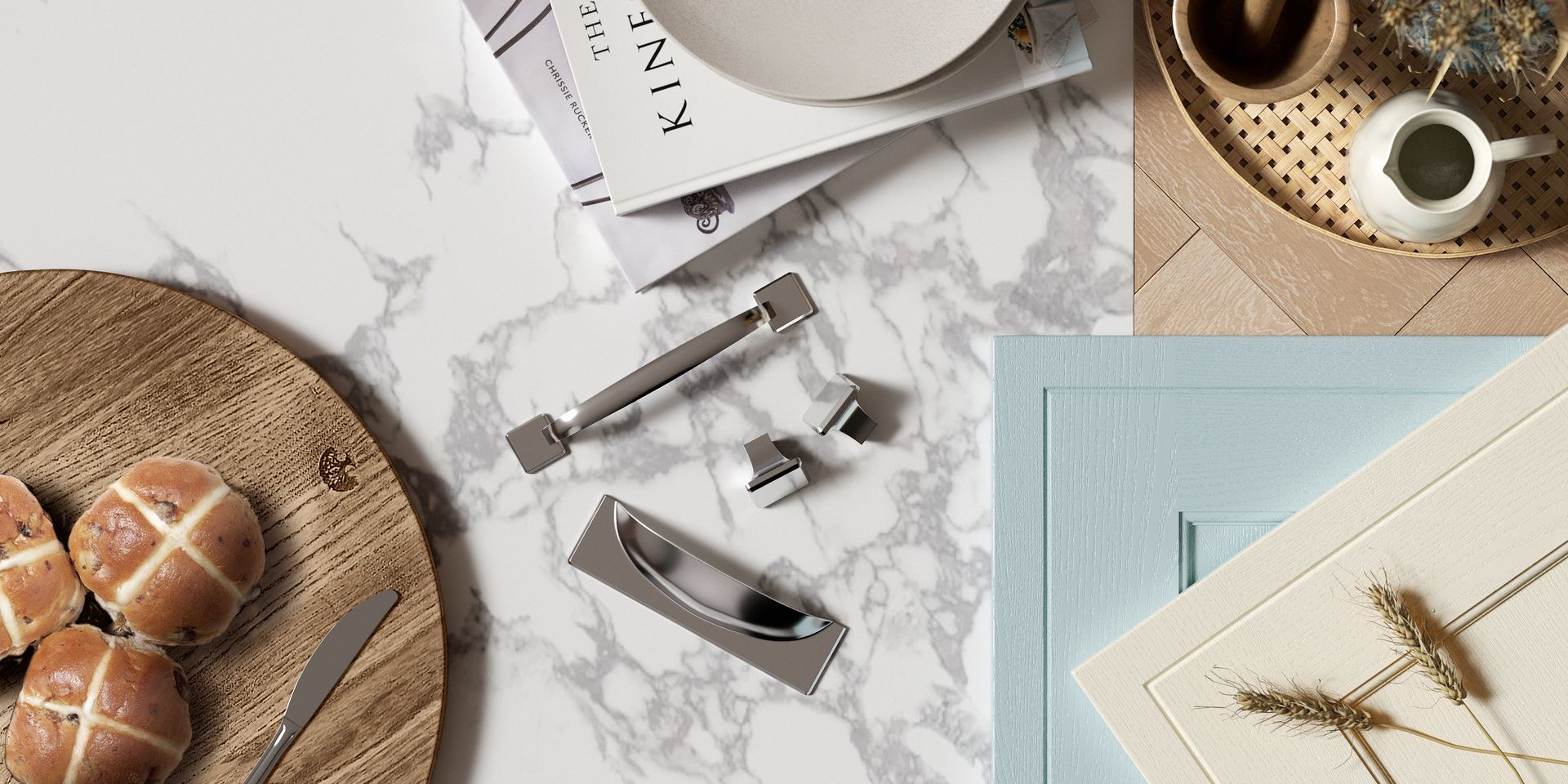 Flat-lay of kitchen cabinet hardware, including handles and knobs, arranged on a white marble surface near bakery items.