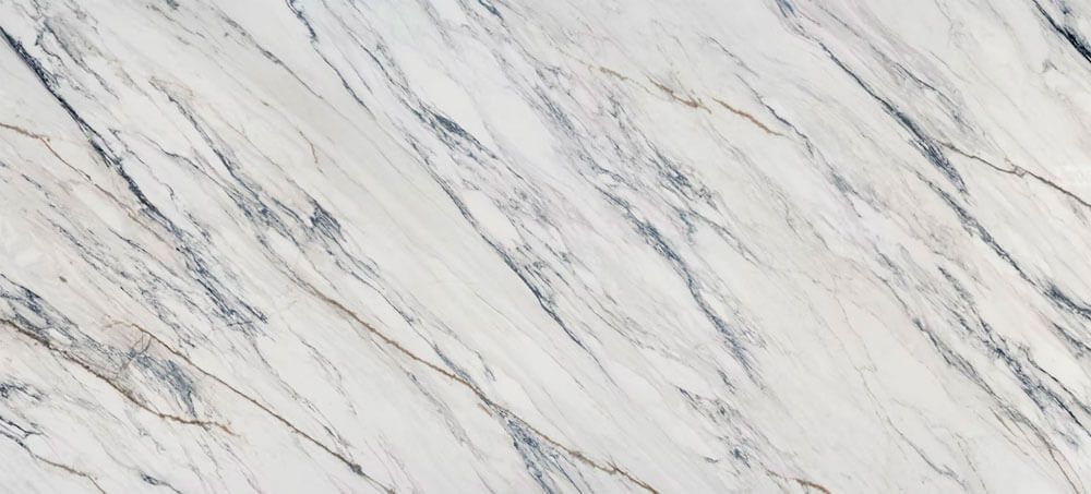 A light-colored marble surface with diagonal veins of grey and subtle golden-brown tones.