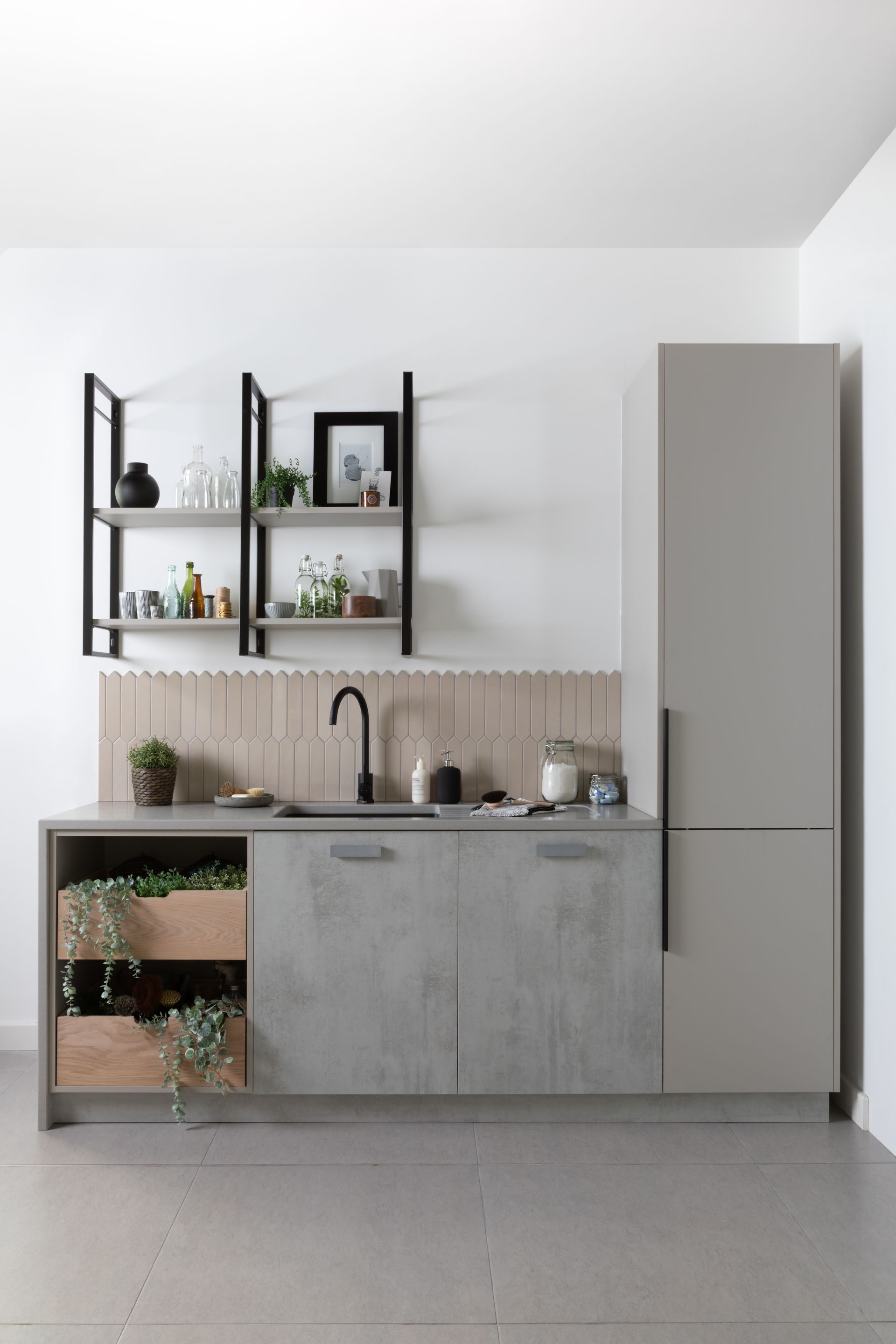 Modern kitchen unit with a grey sink cabinet, integrated wood shelves, a tall grey pantry, and black open wall shelving.