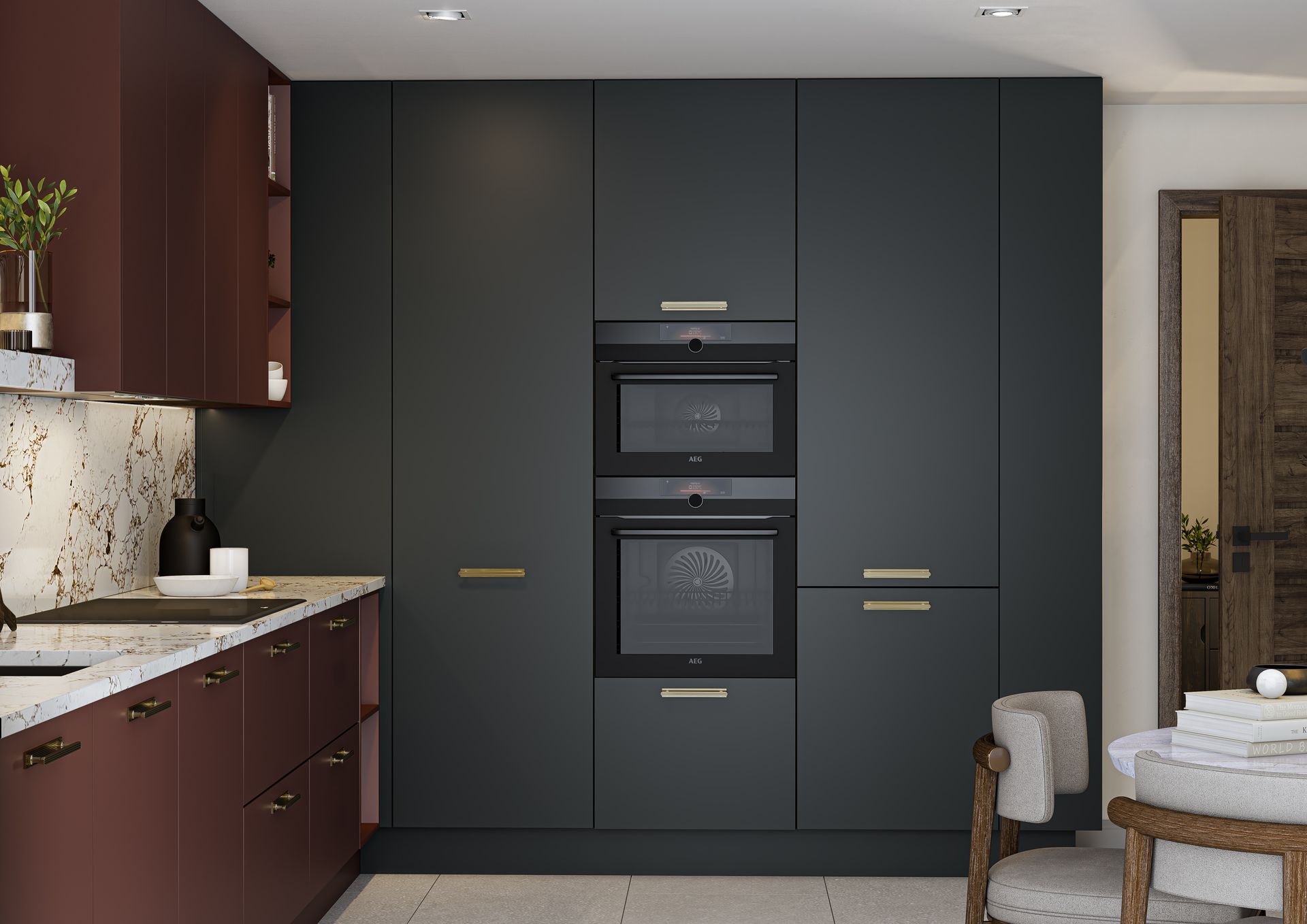A modern kitchen featuring matte charcoal tall cabinets with built-in dual ovens next to deep maroon base cabinets.