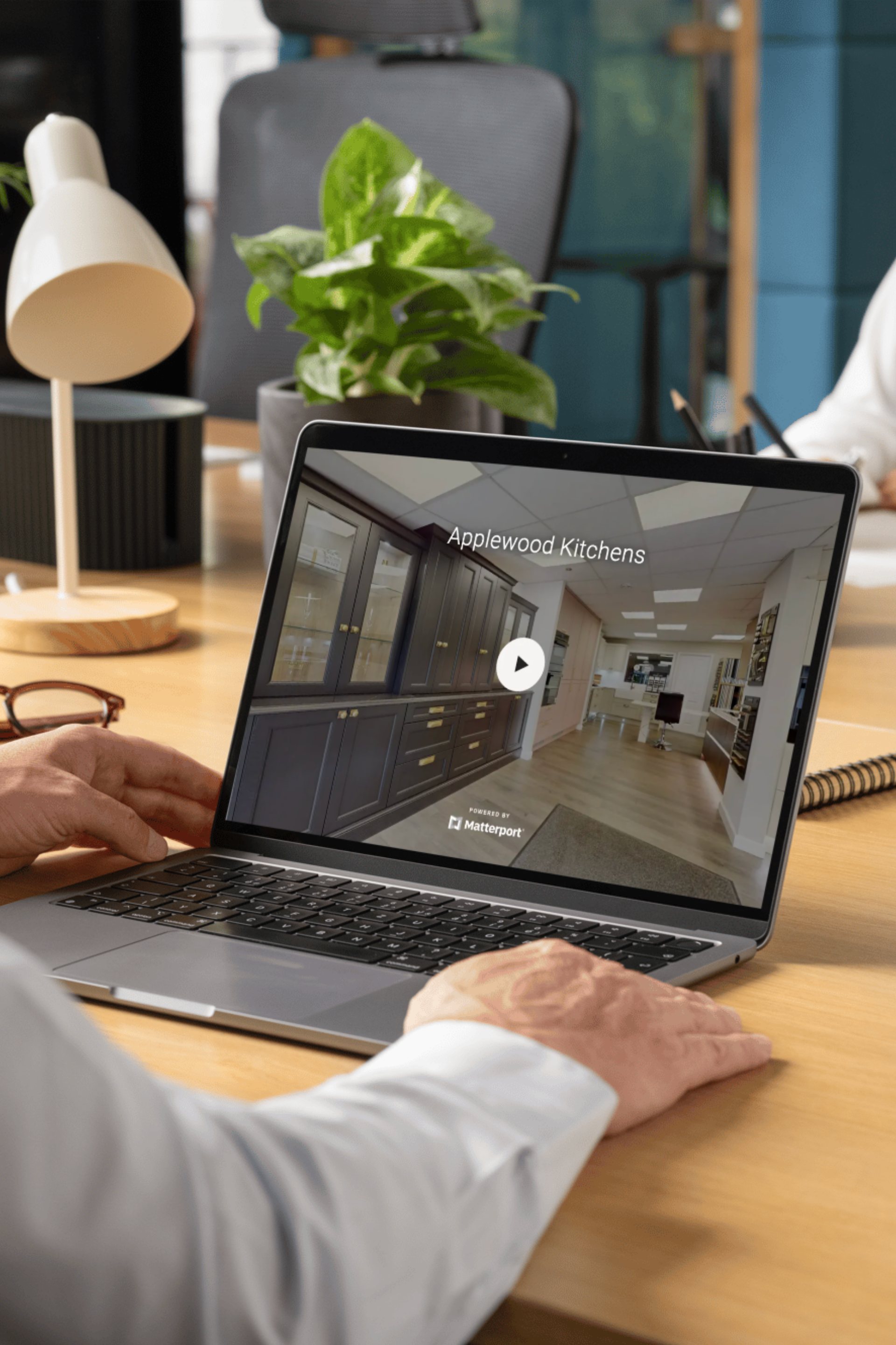 A person working at a desk on a laptop displaying a virtual office tour.
