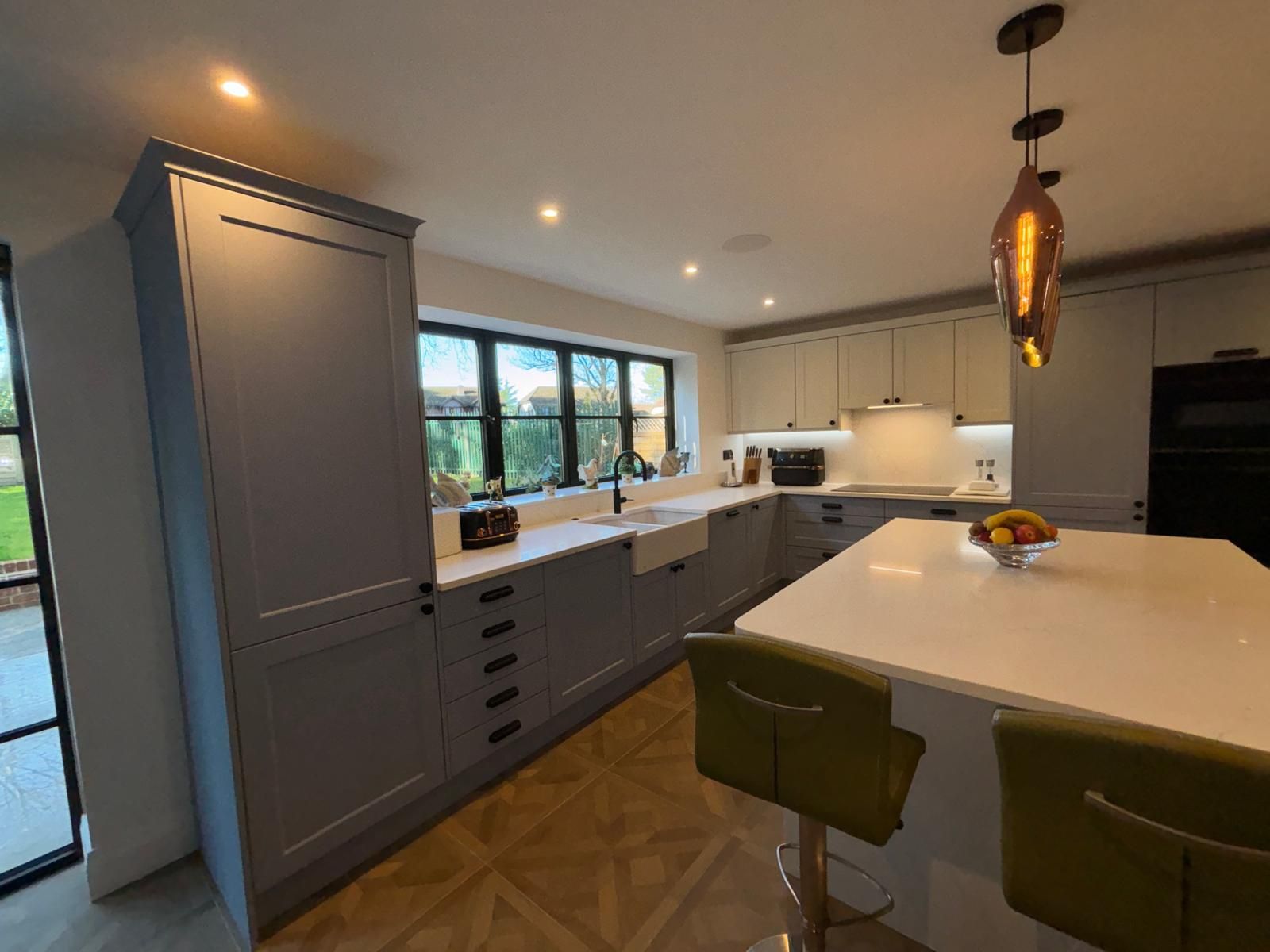 A modern kitchen with blue cabinetry, a white island, wooden flooring, and a pendant light over the counter.