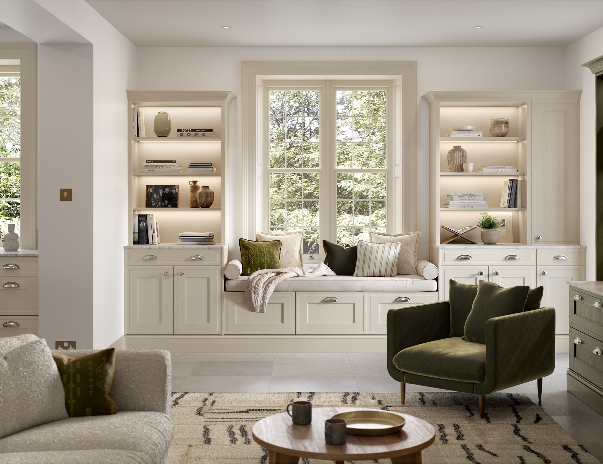 A light-toned living room featuring a window seat between illuminated bookcases, a green armchair, and a rug.