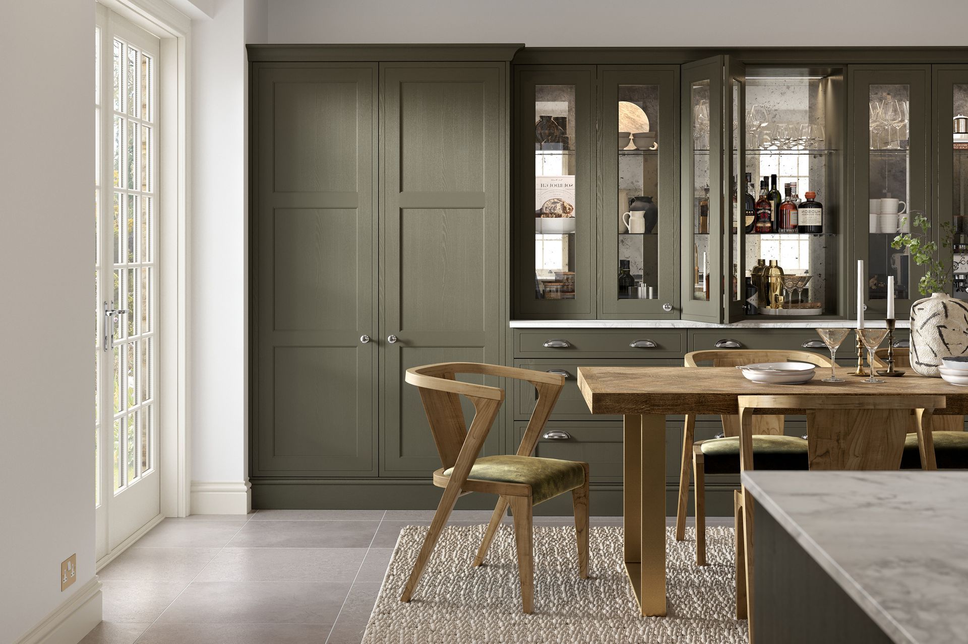 A modern dining area with olive green cabinets, a wooden table, and a sculptural wooden chair on a light rug.