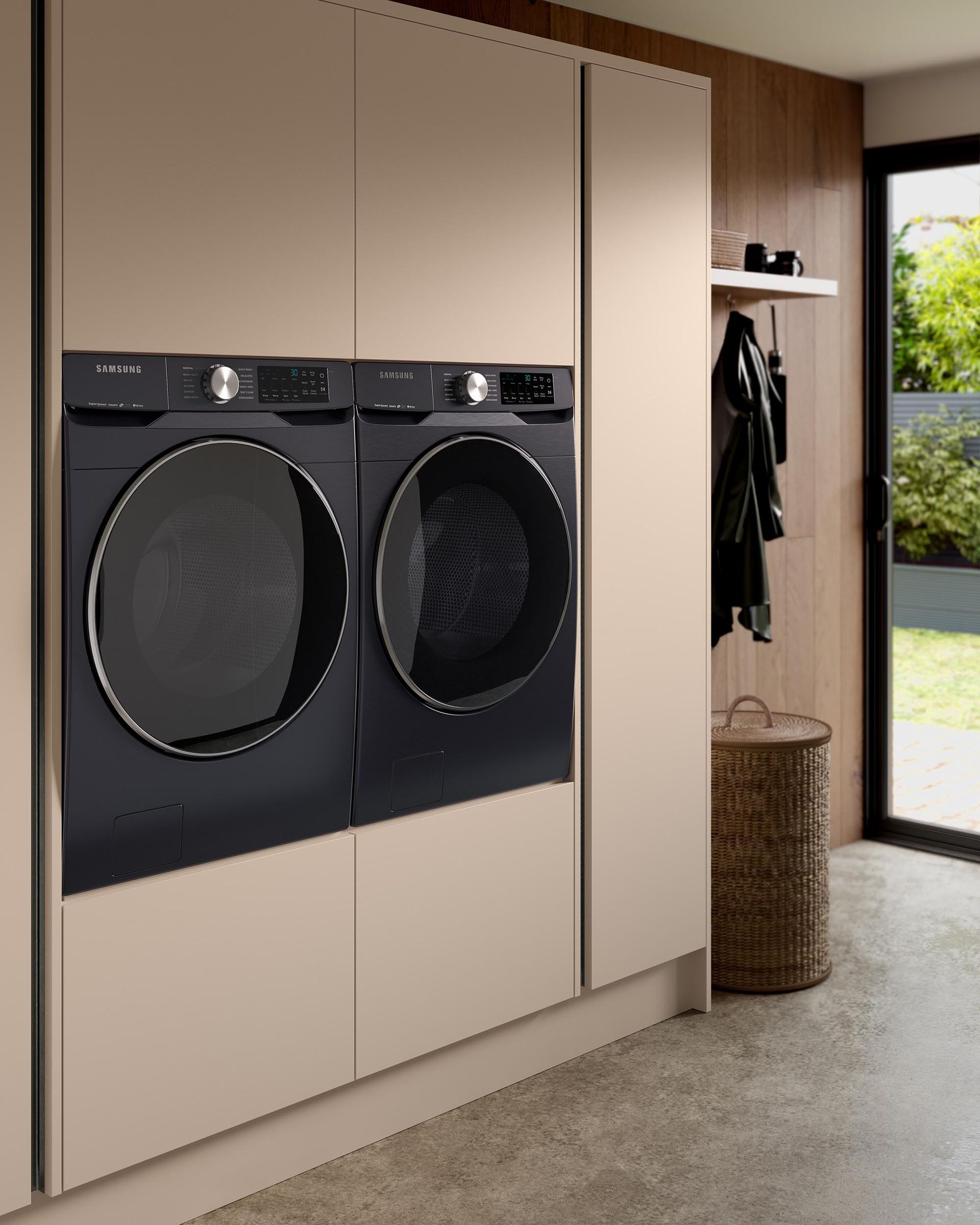 Two sleek, black front-loading laundry machines are built into light-beige cabinetry in a modern, minimalist laundry room.