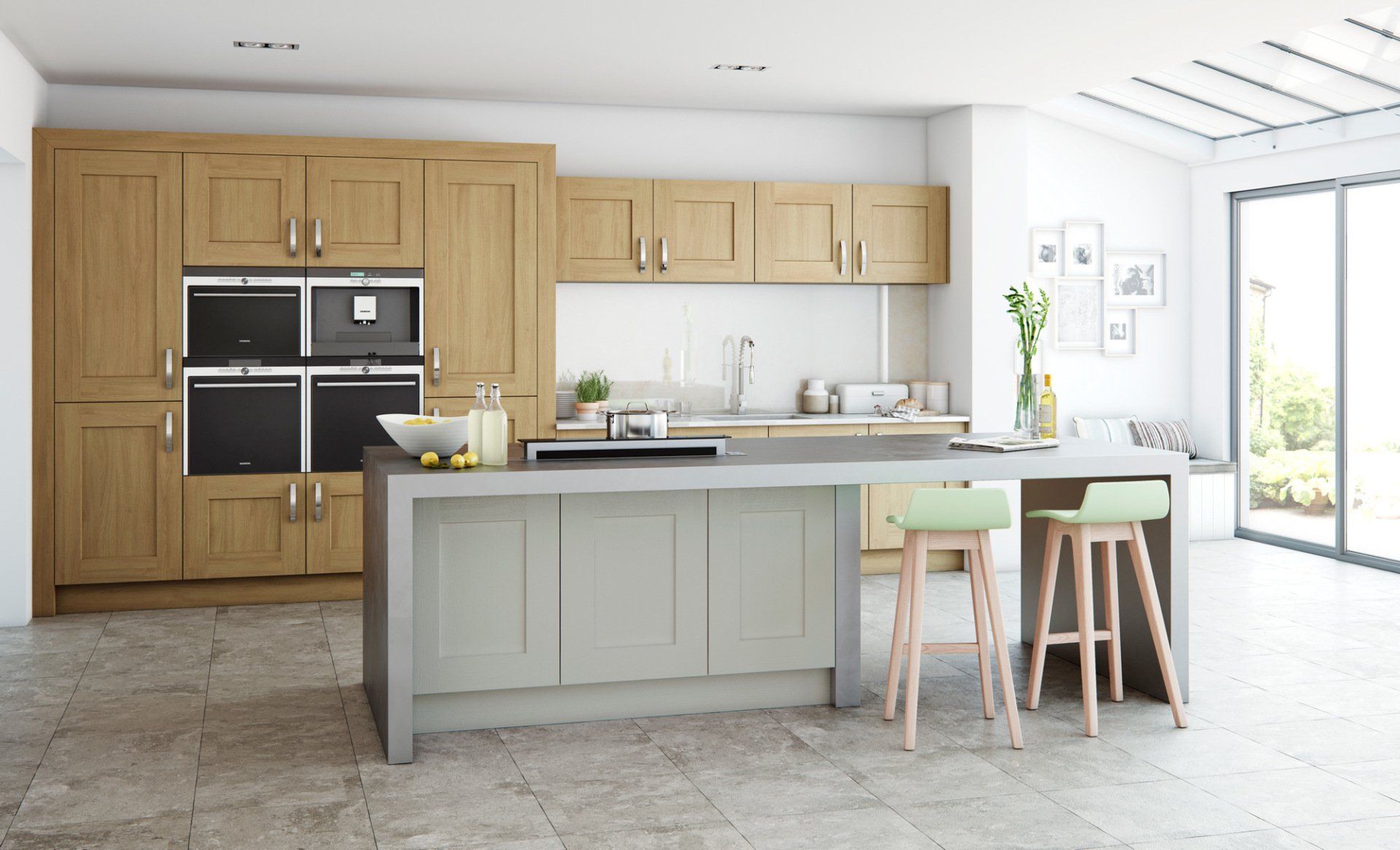 A modern kitchen with oak cabinets, a grey island with two light green stools, and tiled flooring.