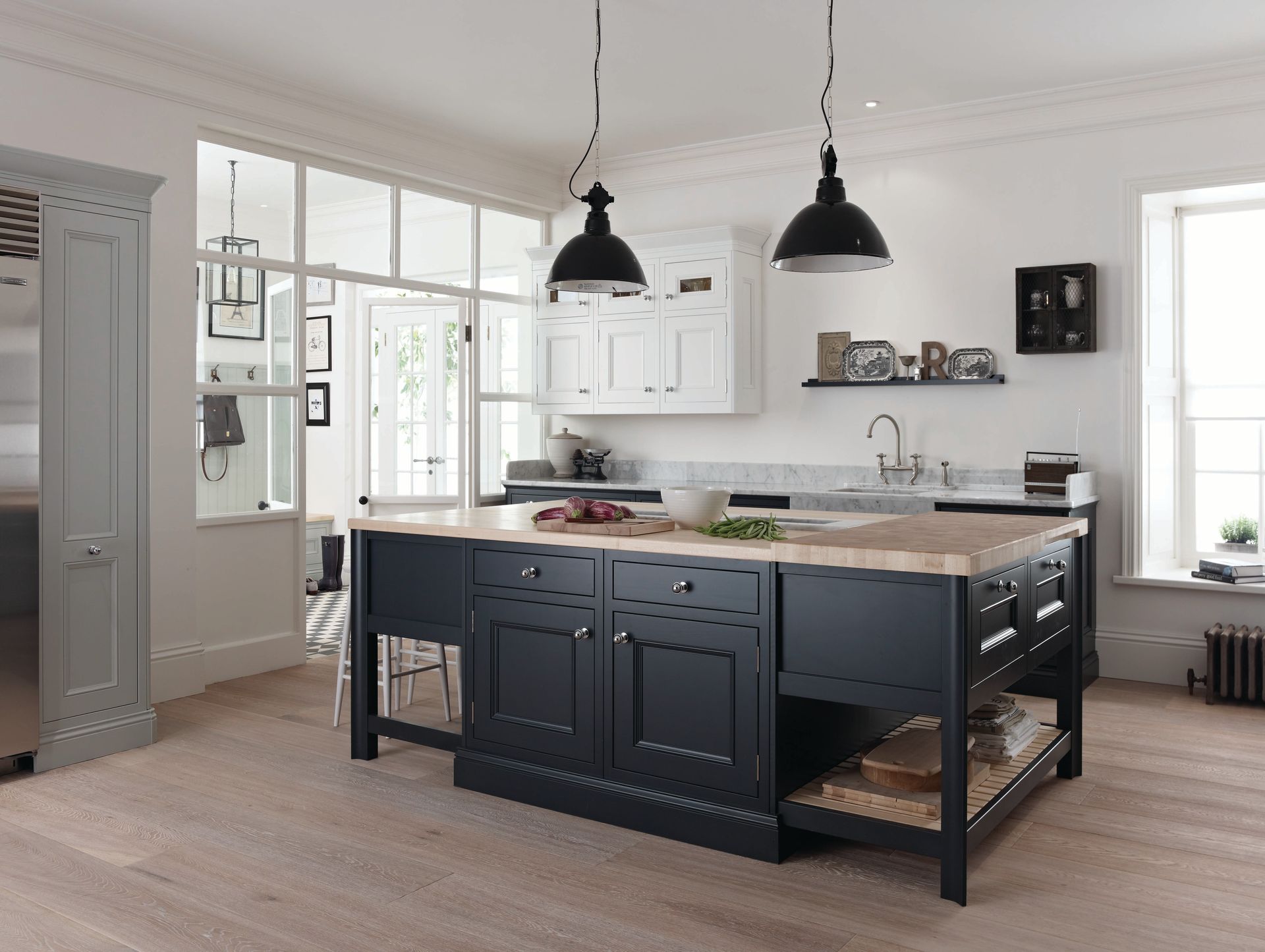 A bright, modern kitchen featuring a large black island with a wooden countertop and two black pendant lights above.