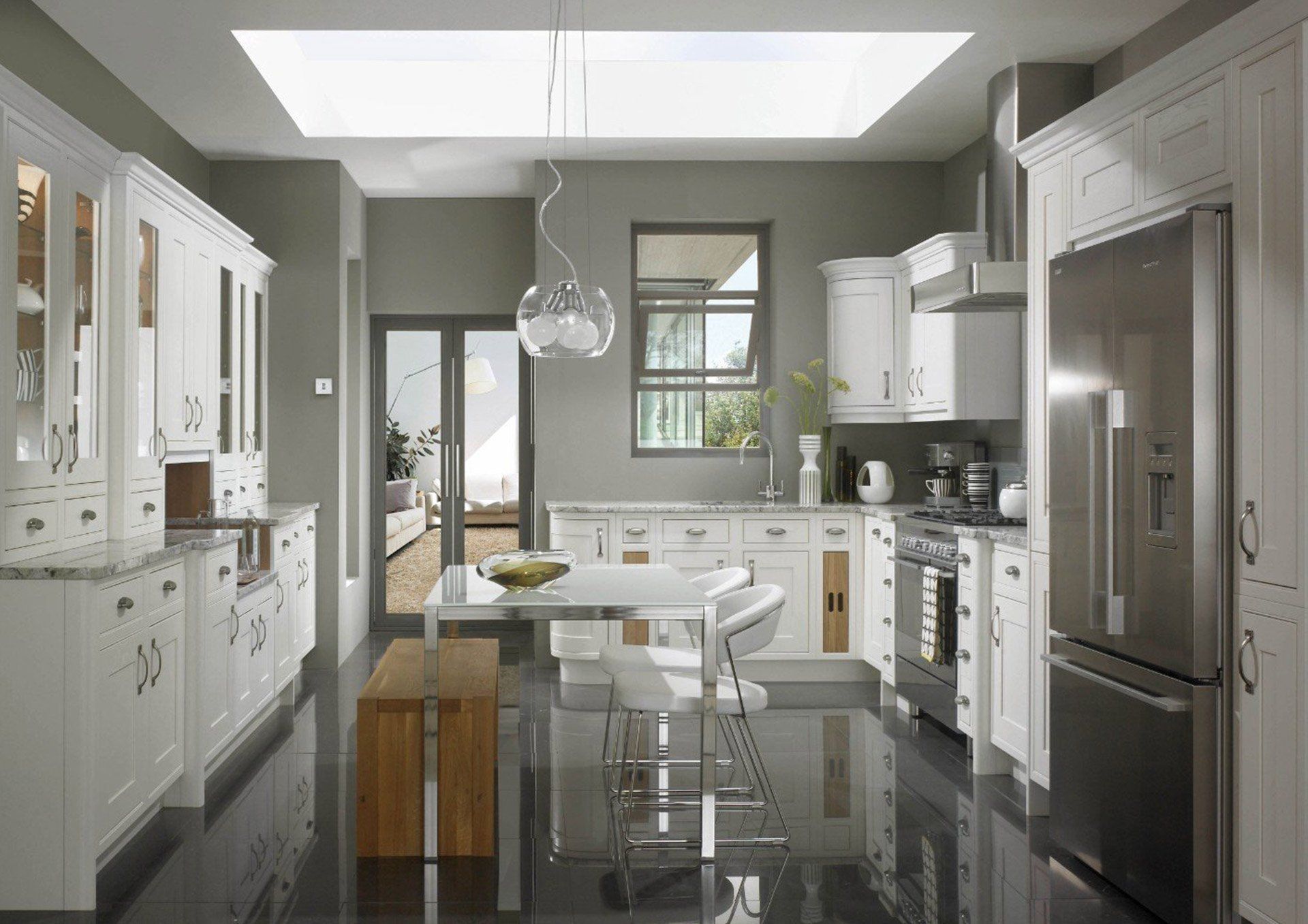 A modern kitchen featuring white cabinets, stainless steel appliances, a wooden bench, and gray walls with a skylight.