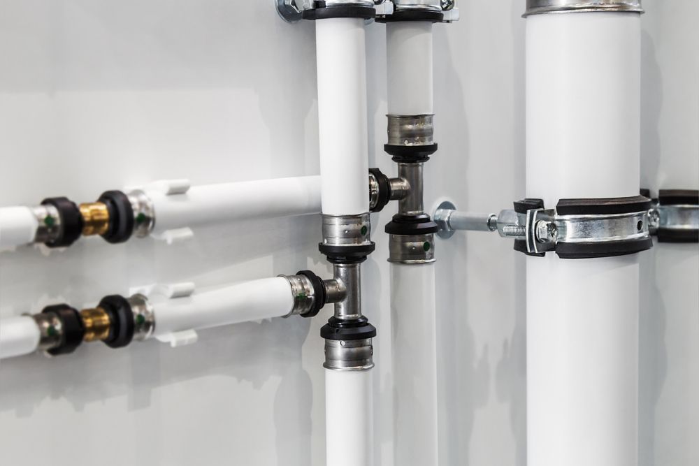 A Close Up Of A Row Of White Pipes Attached To A Wall — Tim Larkin Plumbing and Excavations in Lake Cathie, NSW