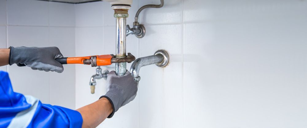 A Plumber Is Fixing A Sink With A Wrench — Tim Larkin Plumbing and Excavations in Lake Cathie, NSW