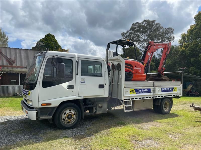 A Work Vehicle With an Excavator On the Tray — Tim Larkin Plumbing and Excavations in Laurieton, NSW