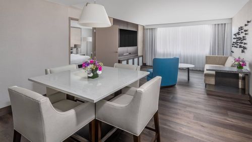 A hotel room with a dining table and chairs in it.