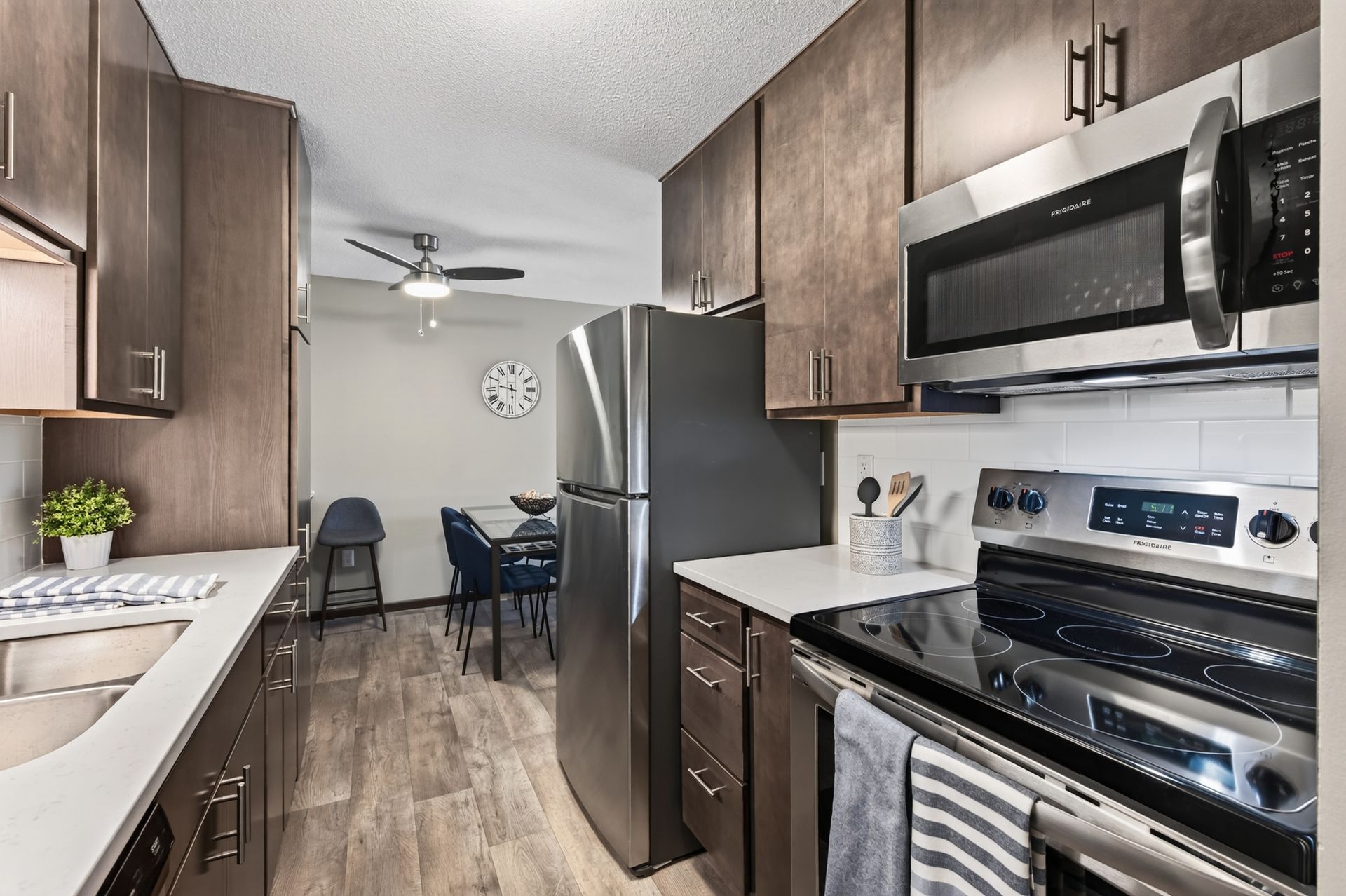 Modern kitchen with stainless steel appliances, wood cabinets, and a view into a dining area
