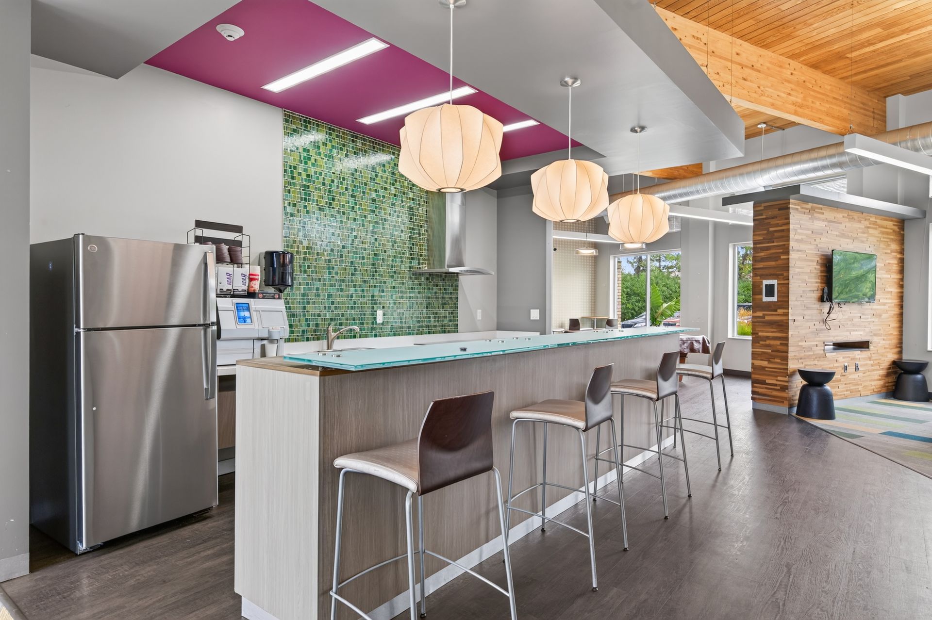 Modern kitchen with island, stools, hanging pendant lights, stainless fridge, and large windows