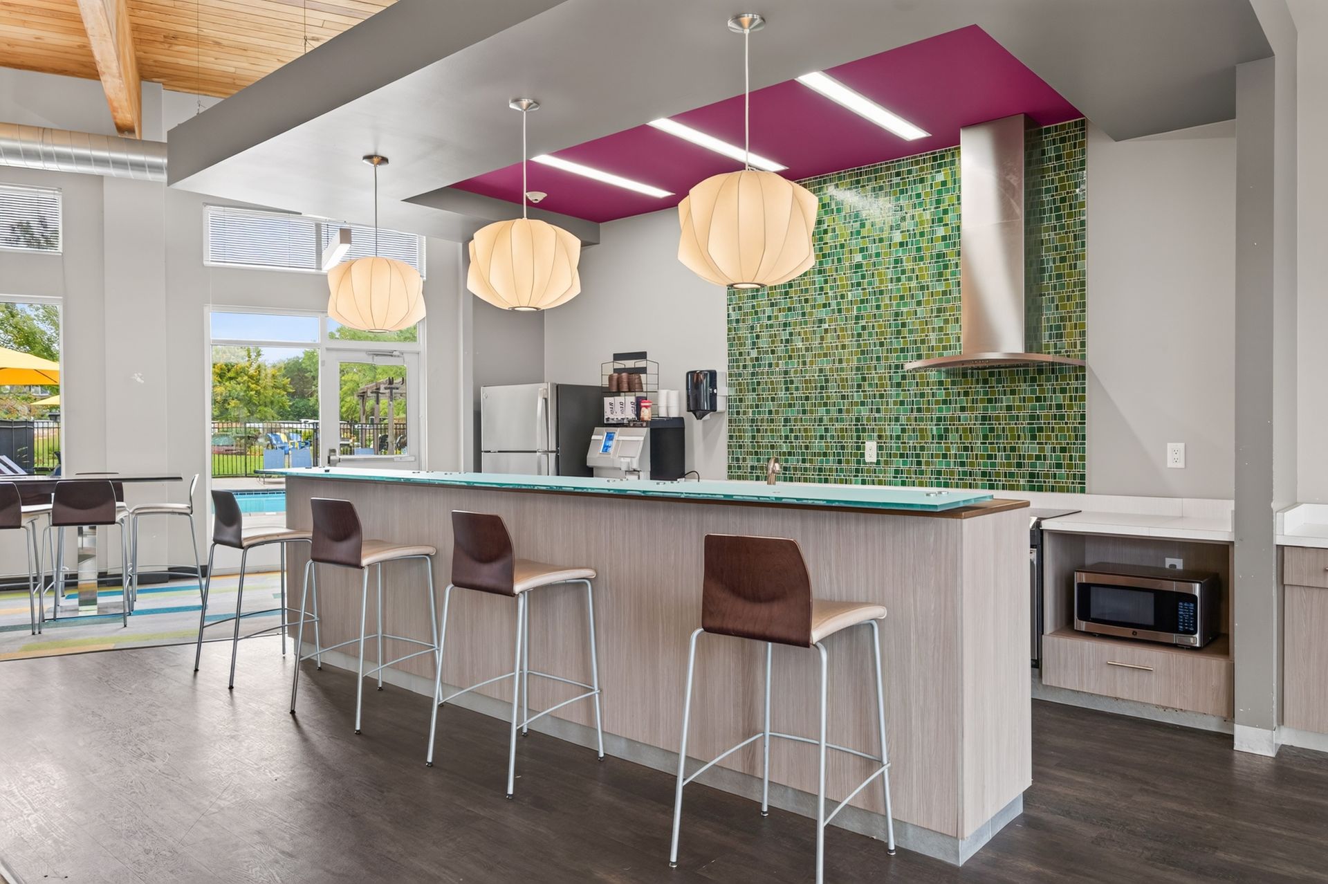 Modern kitchen with magenta ceiling accent, island seating, pendant lights, and living green wall