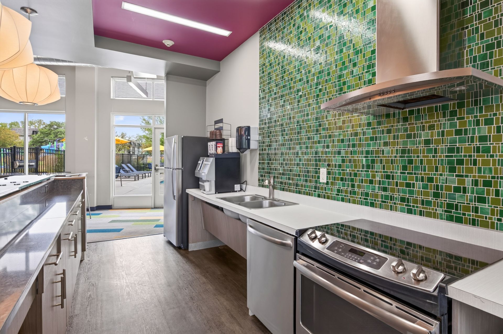 Modern kitchen with green mosaic backsplash, stainless steel appliances, and bright glass doors