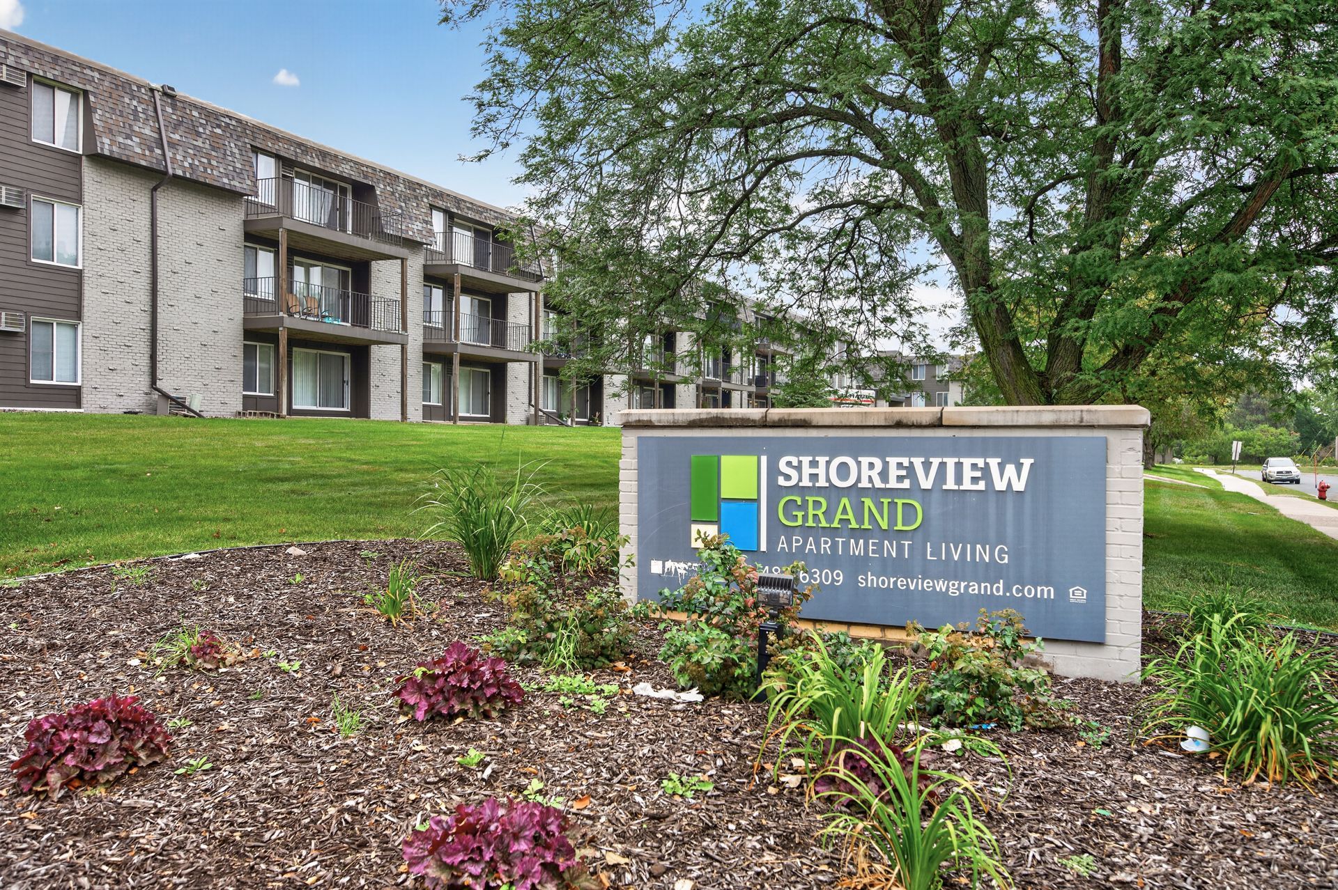 Shoreview Grand apartment sign in front of a beige building and landscaped garden.