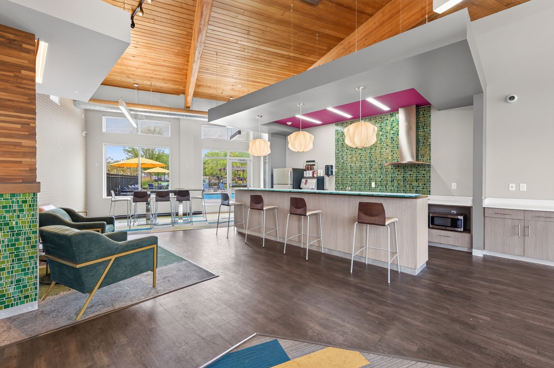 Modern open-plan kitchen and living room with white island, bar stools, dark wood floors, and vaulted wood ceiling