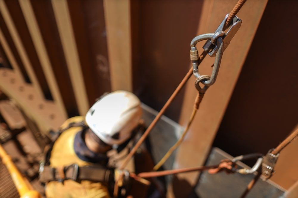 Man Wearing A Helmet And Safety Gear Climbing A Ladder — Calibre Engineering In Darwin, NT
