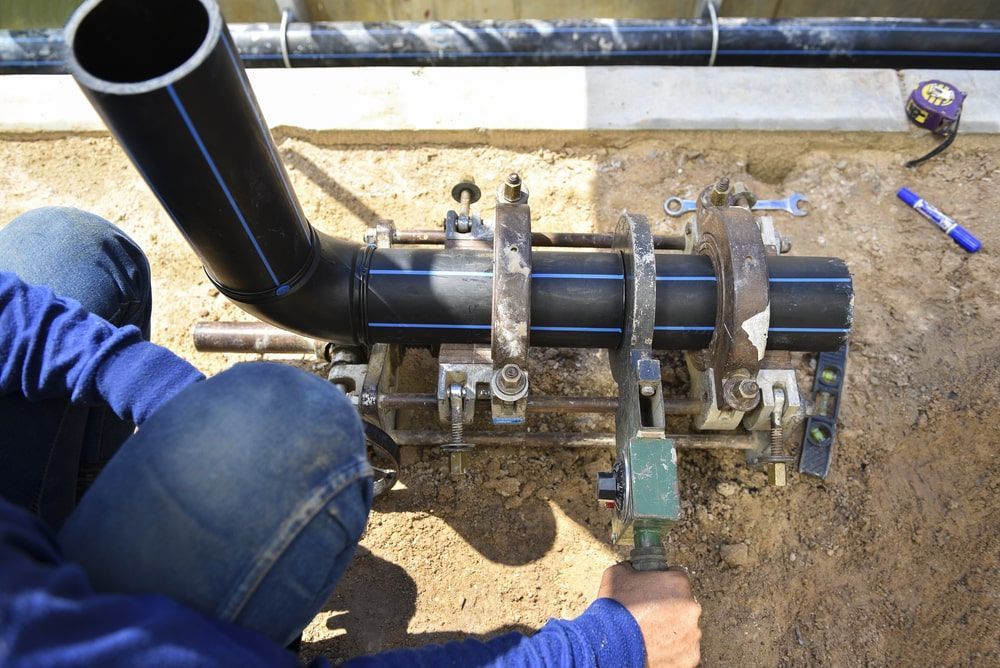 Man Working On A Pipe In The Dirt — Calibre Engineering In Mica Creak, QLD