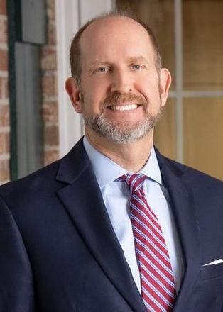 A man in a suit and tie is smiling for the camera.