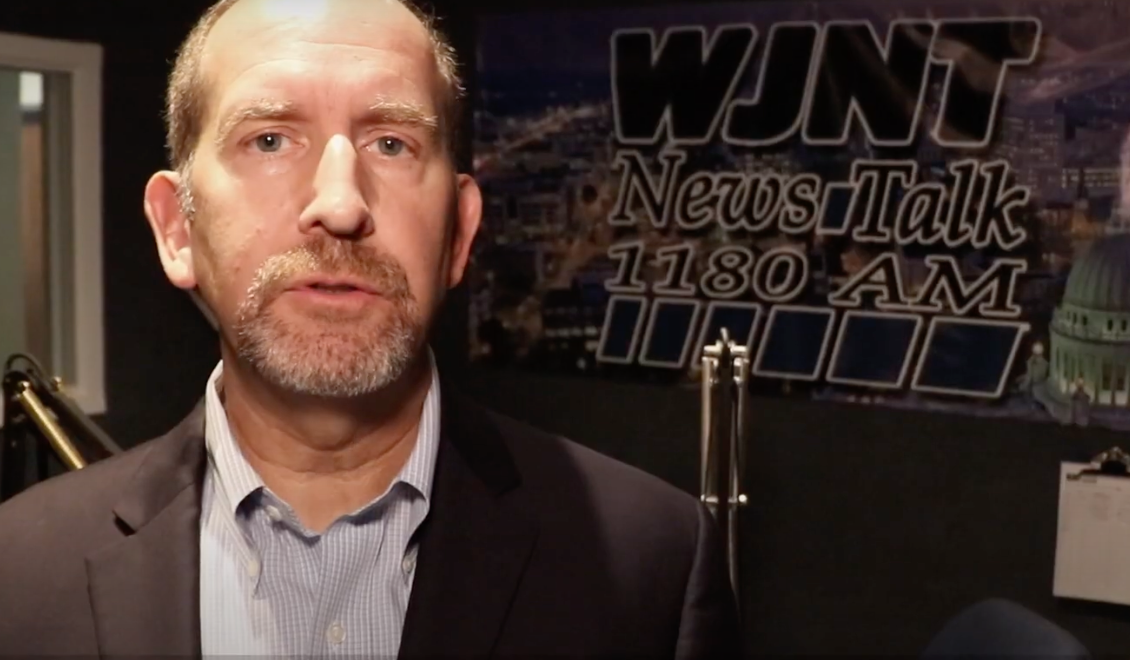 A man in a suit is standing in front of a sign that says wint news talk