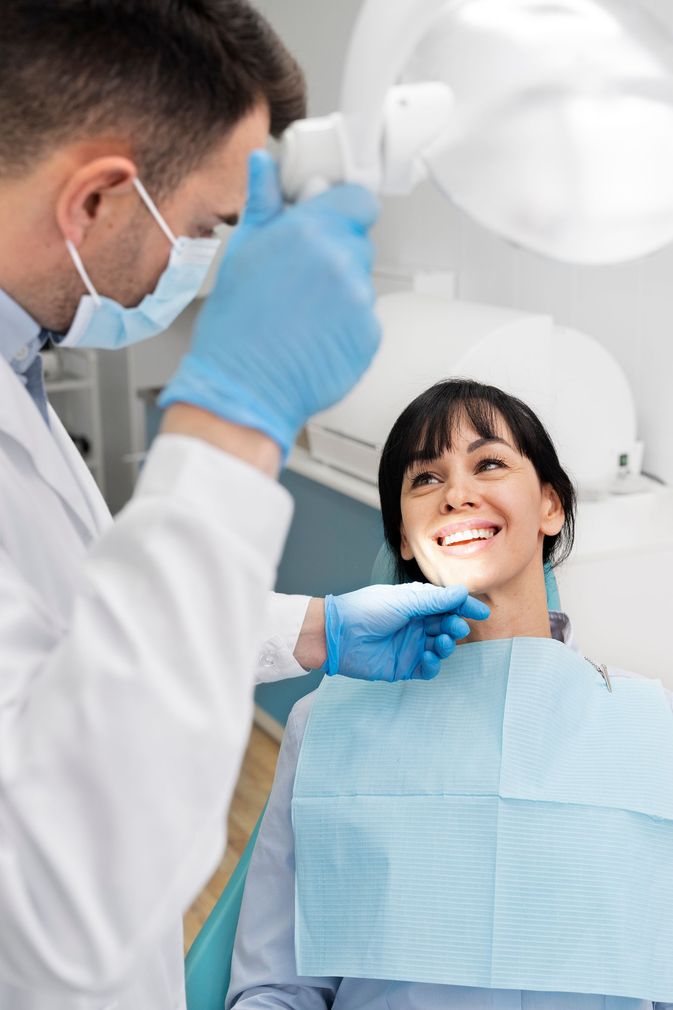 Una donna è seduta sulla poltrona del dentista mentre un dentista le esamina i denti. - Arte Dentale Frosinone