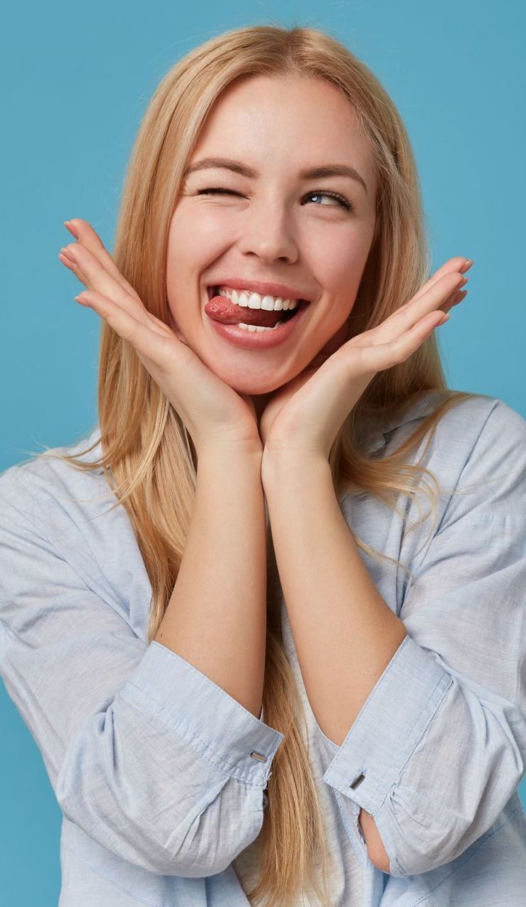 Una donna fa una faccia buffa e tira fuori la lingua - Arte Dentale Frosinone