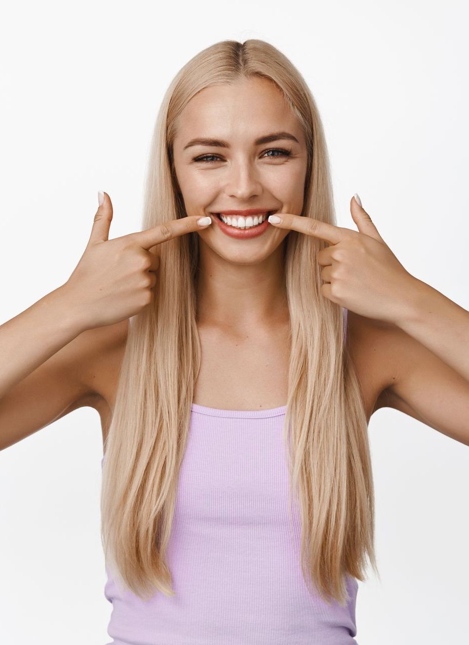 Una donna indica i suoi denti e sorride - Arte Dentale Frosinone