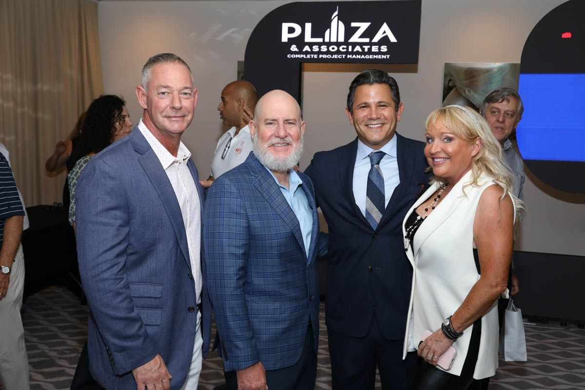 A group of people posing for a picture in front of a sign that says plaza