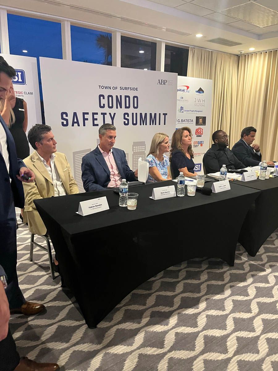 A group of people are sitting at a table at a condo safety summit.